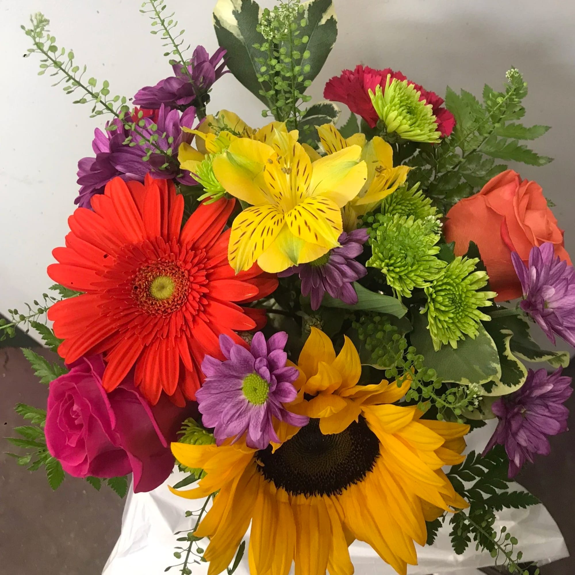 Colorful bouquet with sunflowers, gerbera daisies, roses, and purple blooms