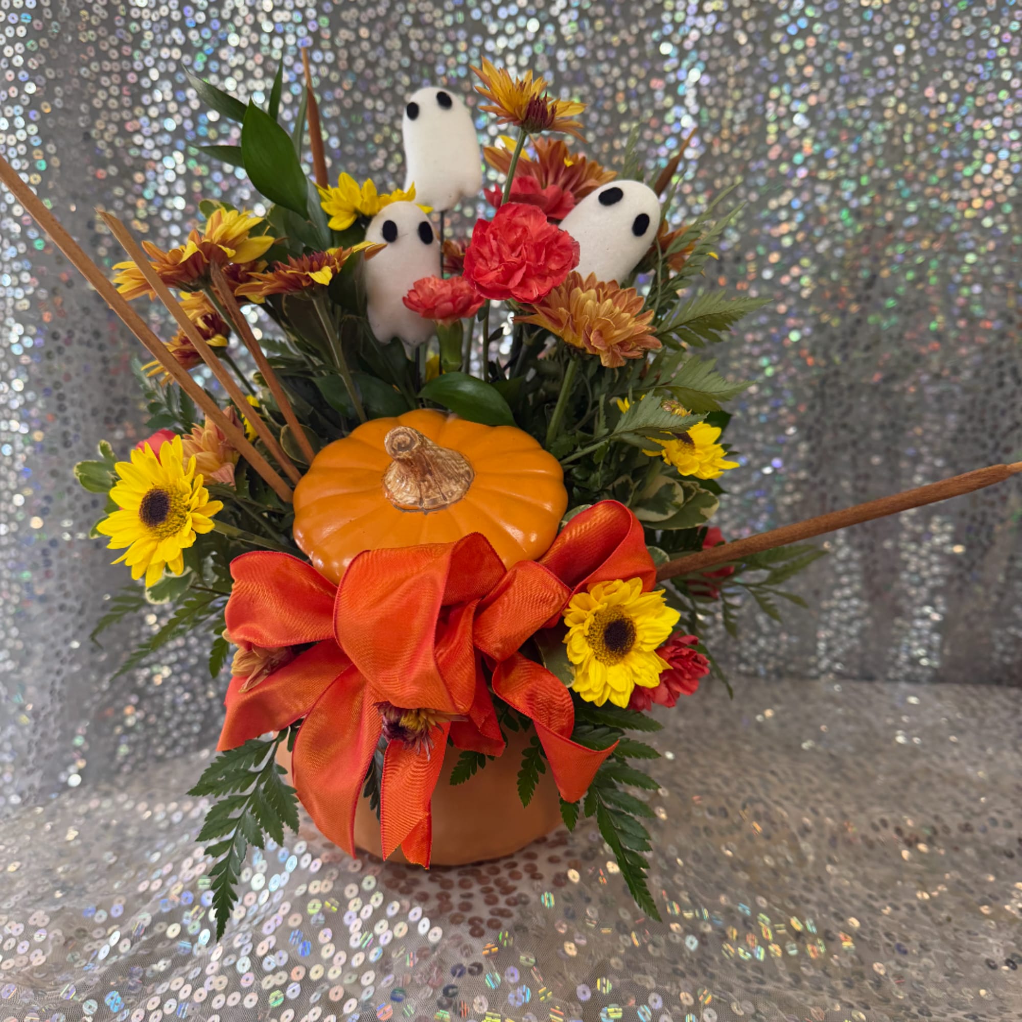 Halloween floral arrangement with a pumpkin, ghost picks, and orange ribbon