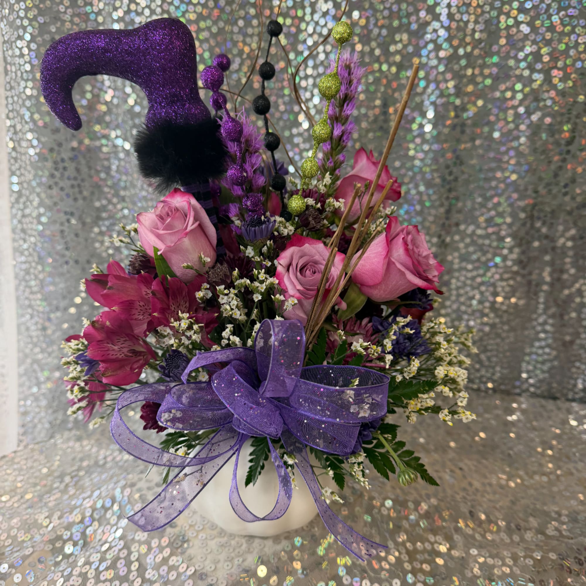 Pink roses and purple flowers in a white vase with a glittery purple hat topper