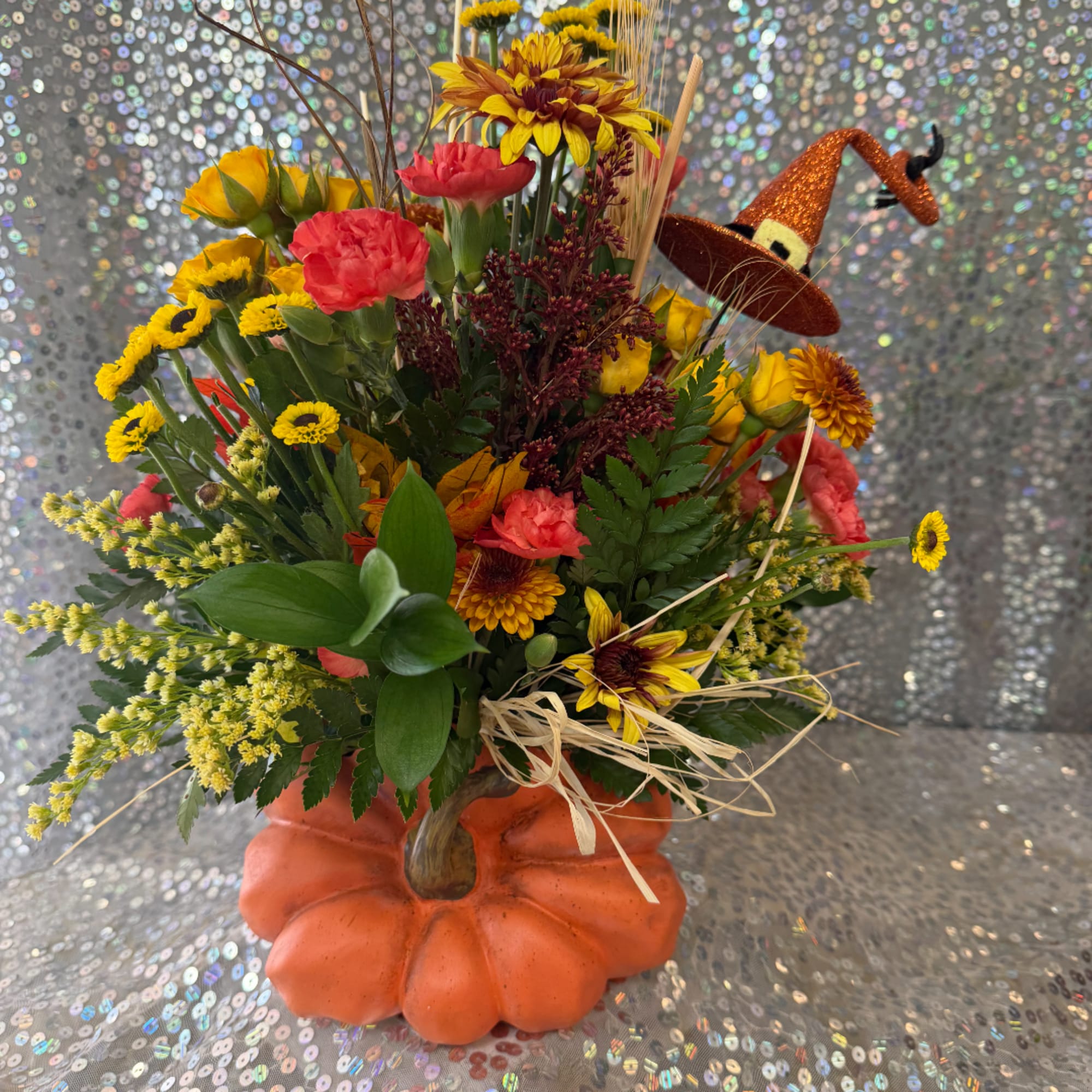 Fall bouquet in a pumpkin vase with a glitter witch hat accent