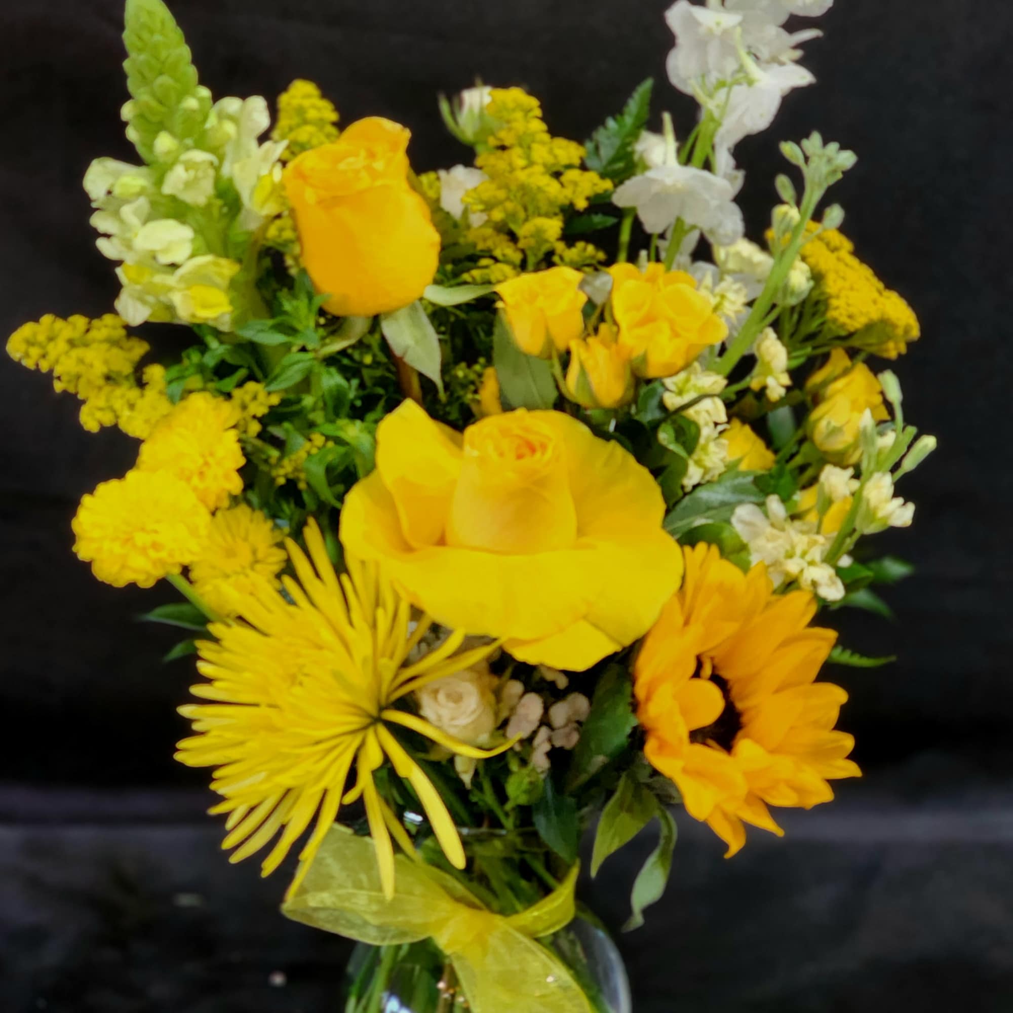 Yellow mixed bouquet in a clear glass vase with white accents