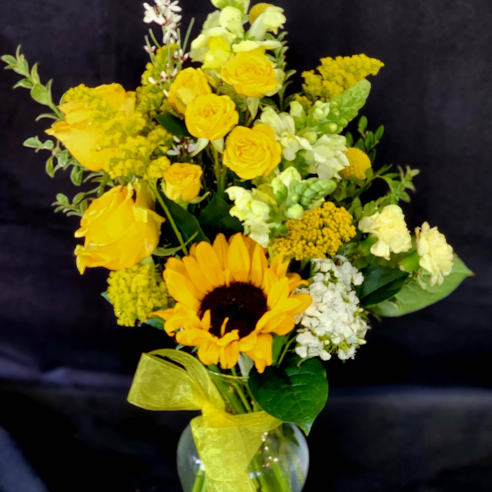 Yellow bouquet with a sunflower and roses in a glass vase