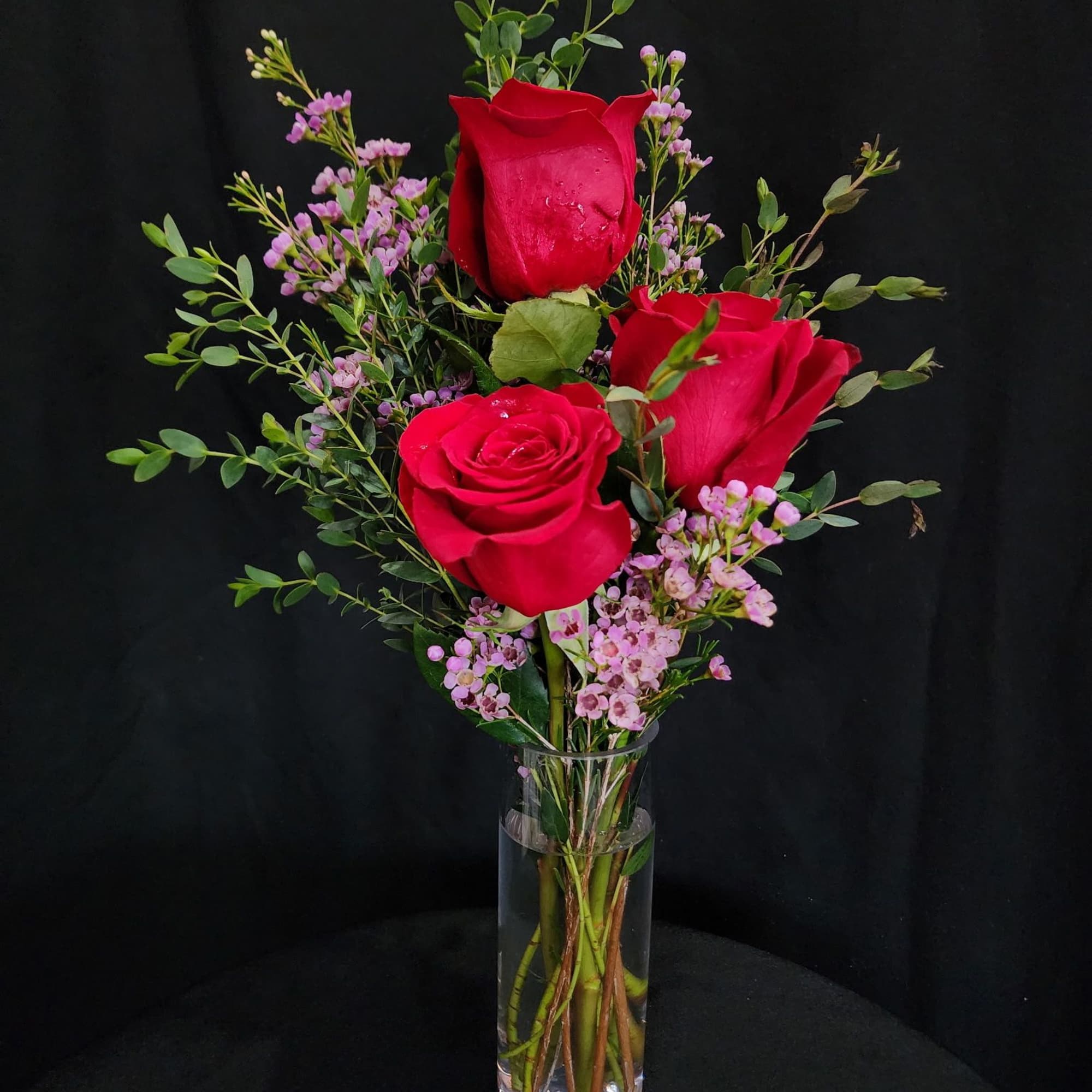 3 red roses in a bud vase with the citrus fragrance of