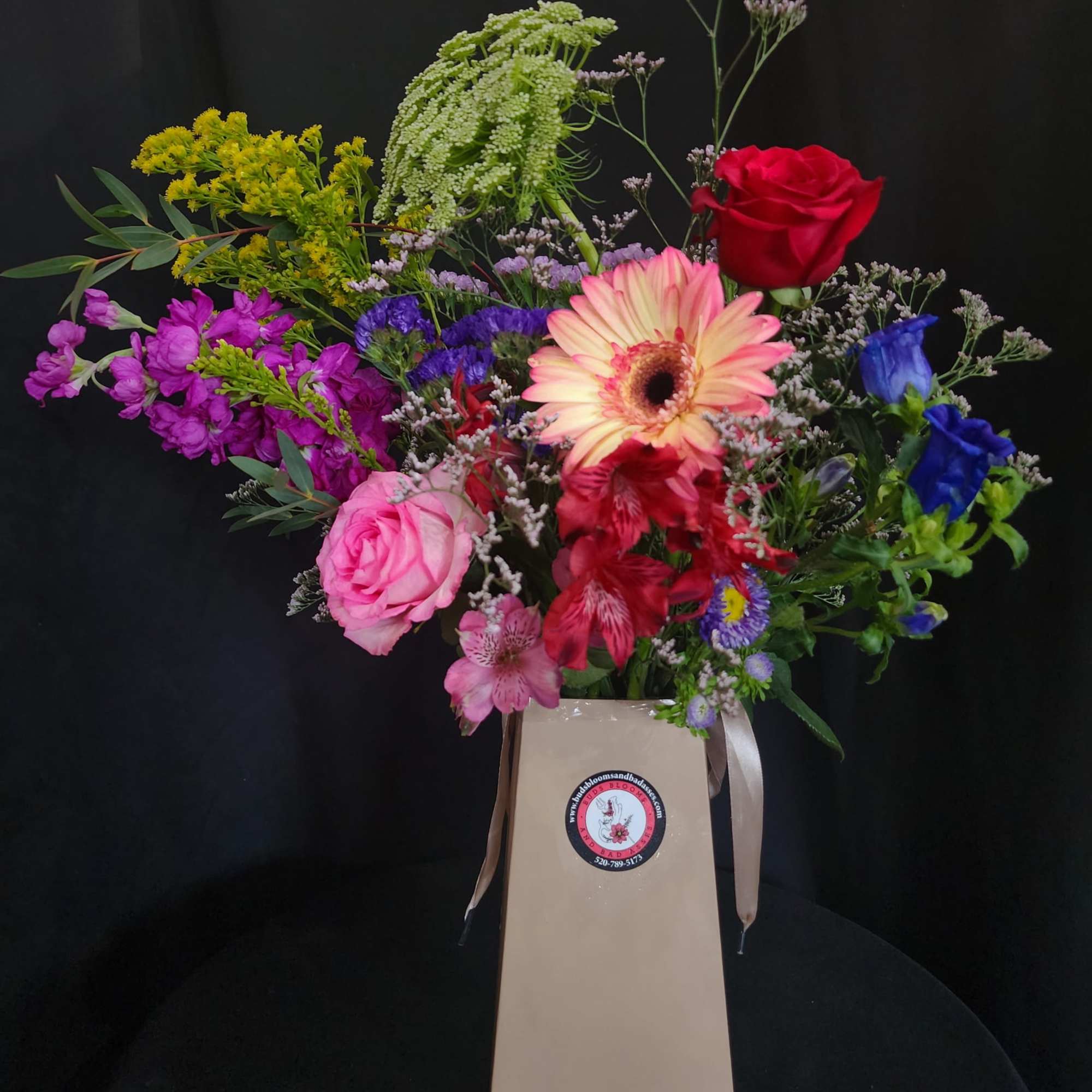 Mixed bouquet in a tall beige gift bag with a ribbon