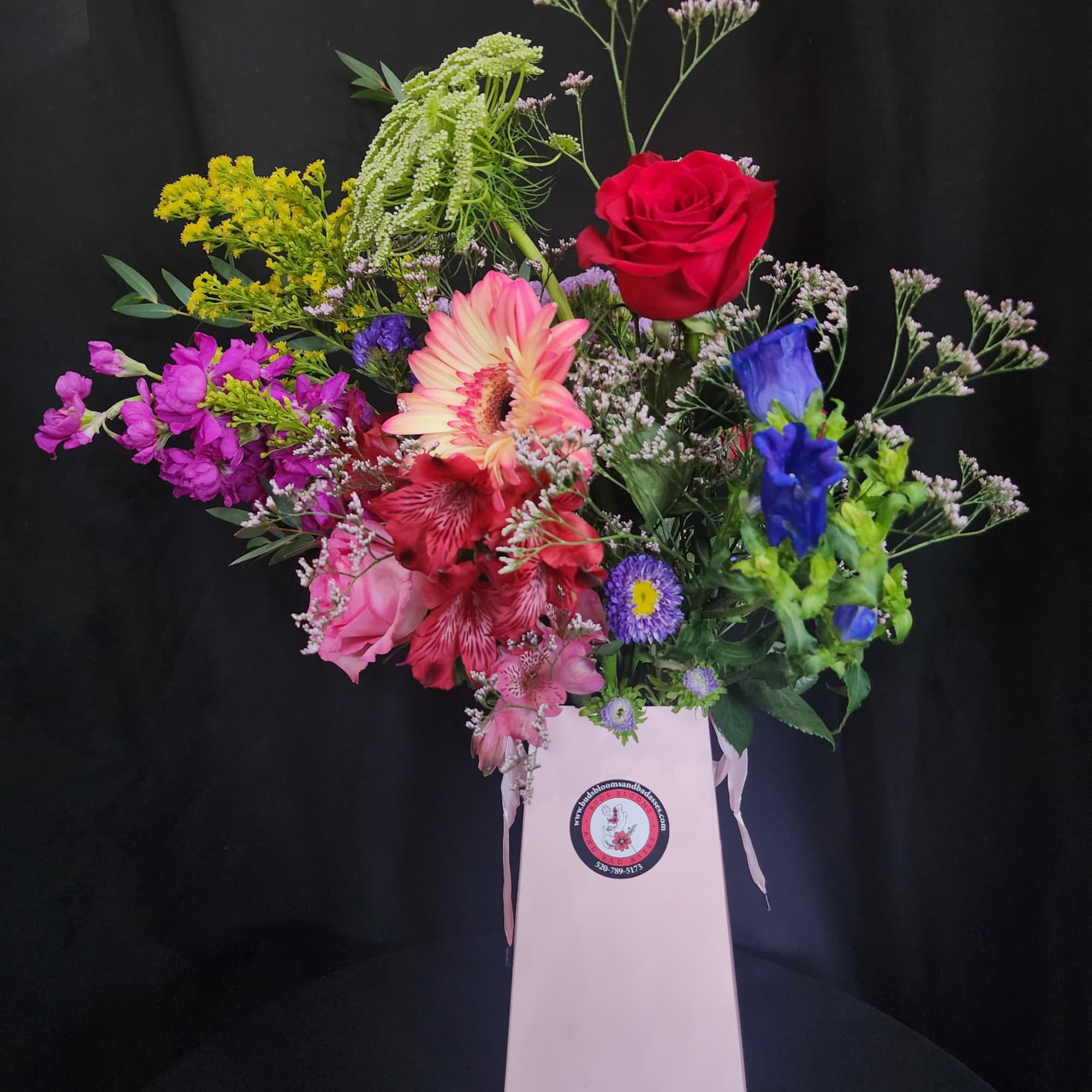 Mixed bouquet in a pink gift box with red, pink, purple, and blue flowers