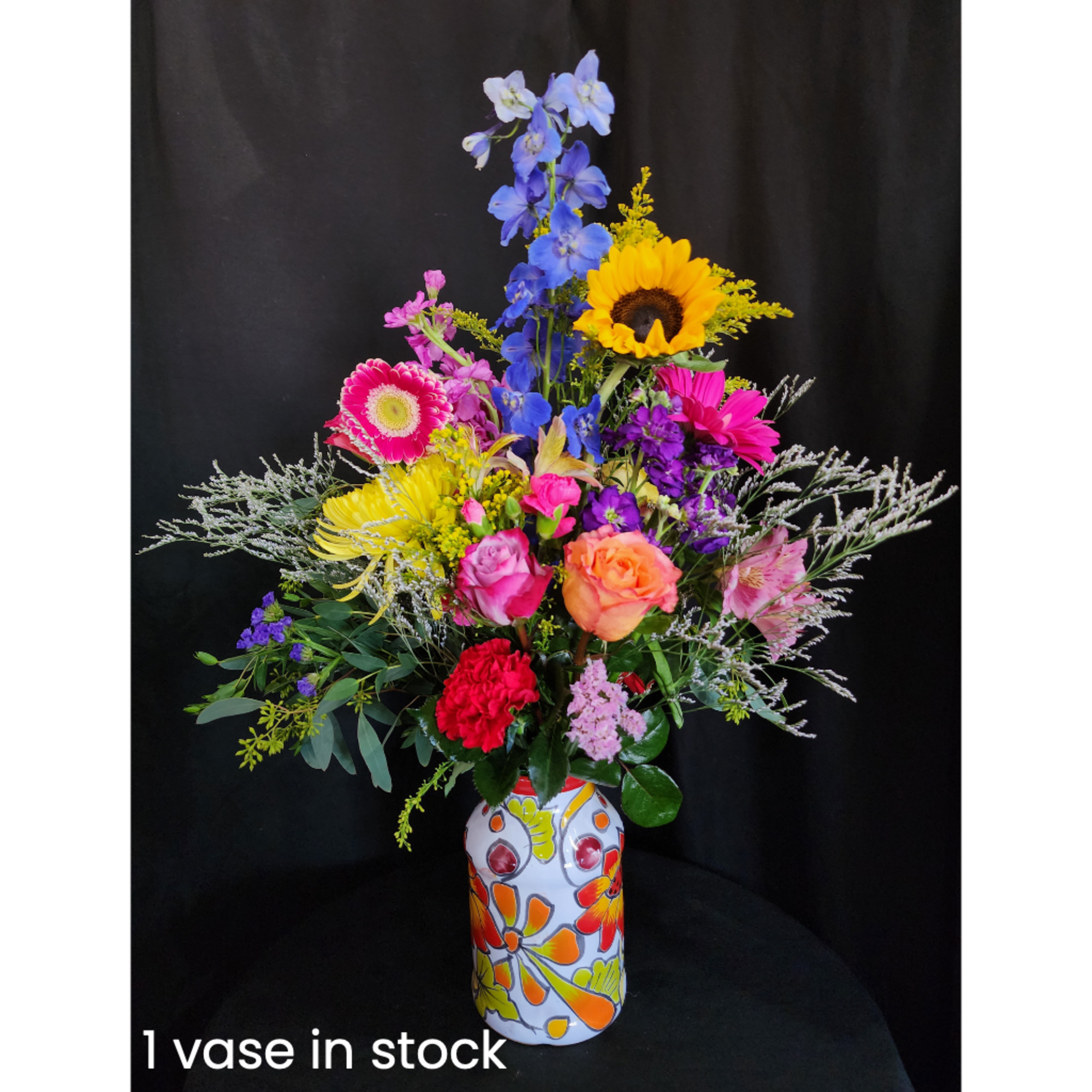Colorful mixed bouquet in a painted vase against a black background