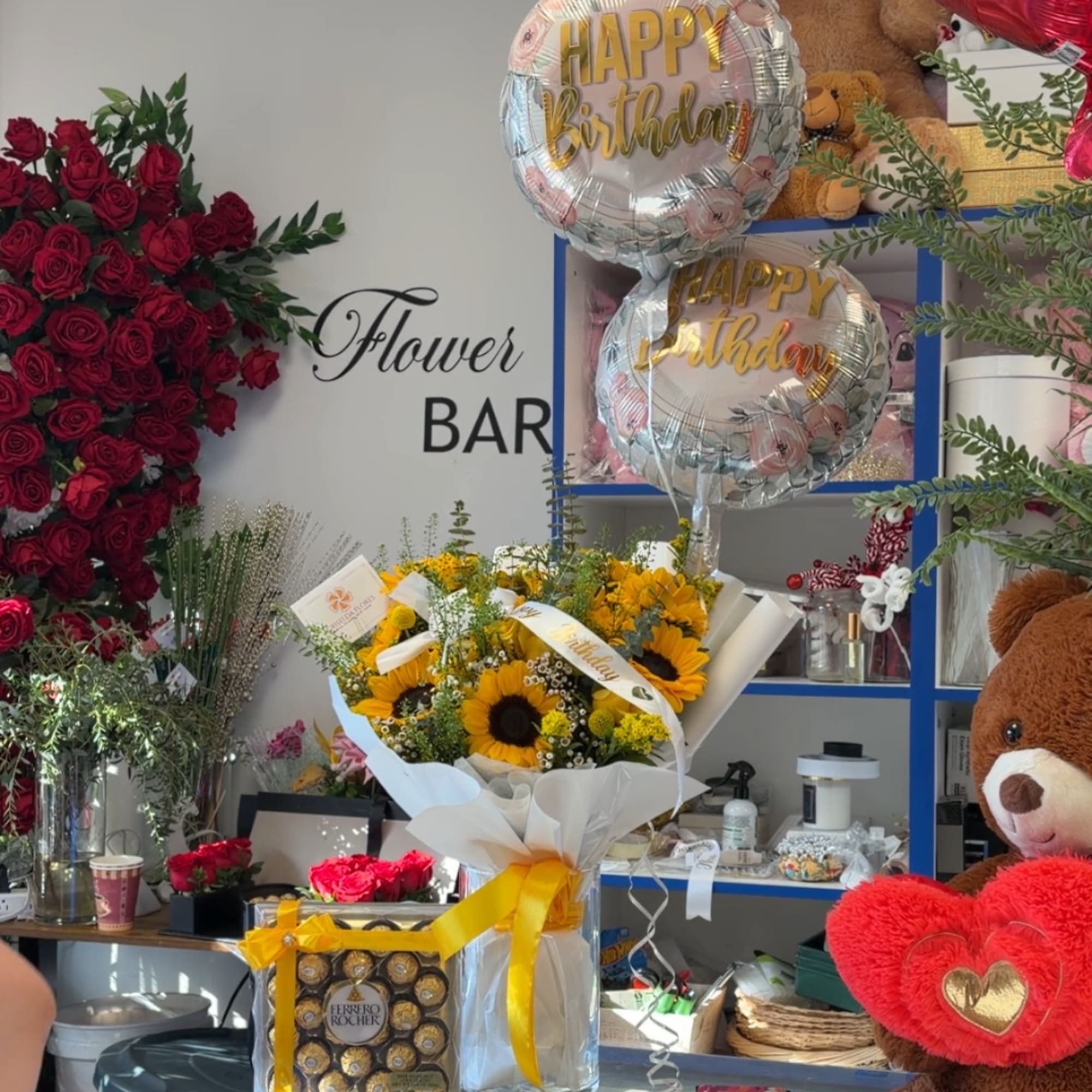 Sunflower bouquet with birthday balloons and teddy bears in a shop display