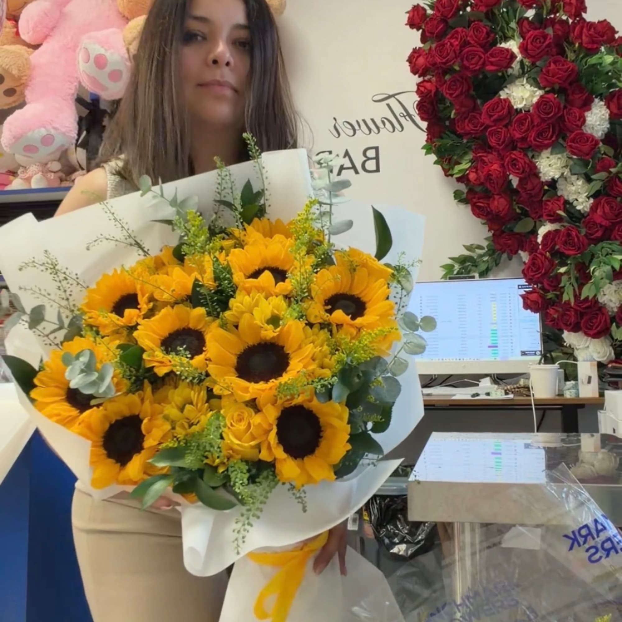 Woman holding a bouquet of sunflowers wrapped in white paper