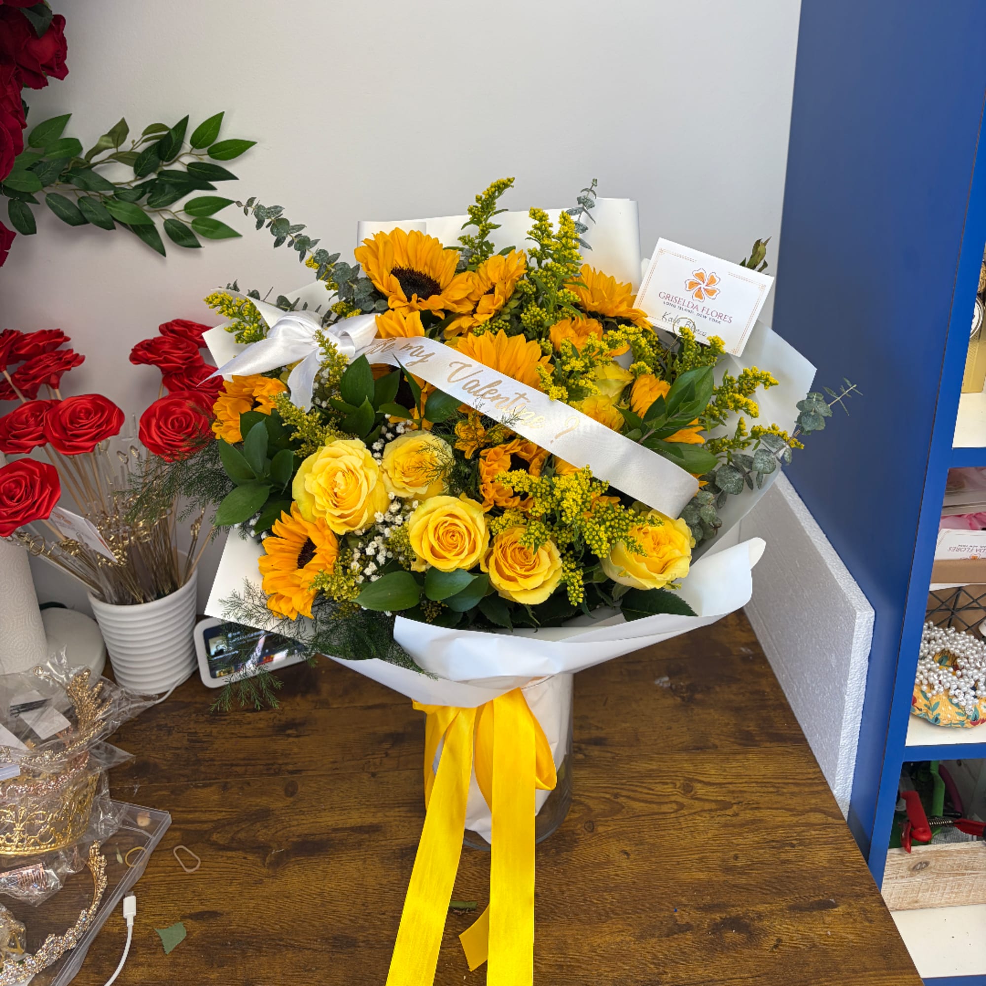 Yellow roses and sunflowers in white wrap with a yellow ribbon