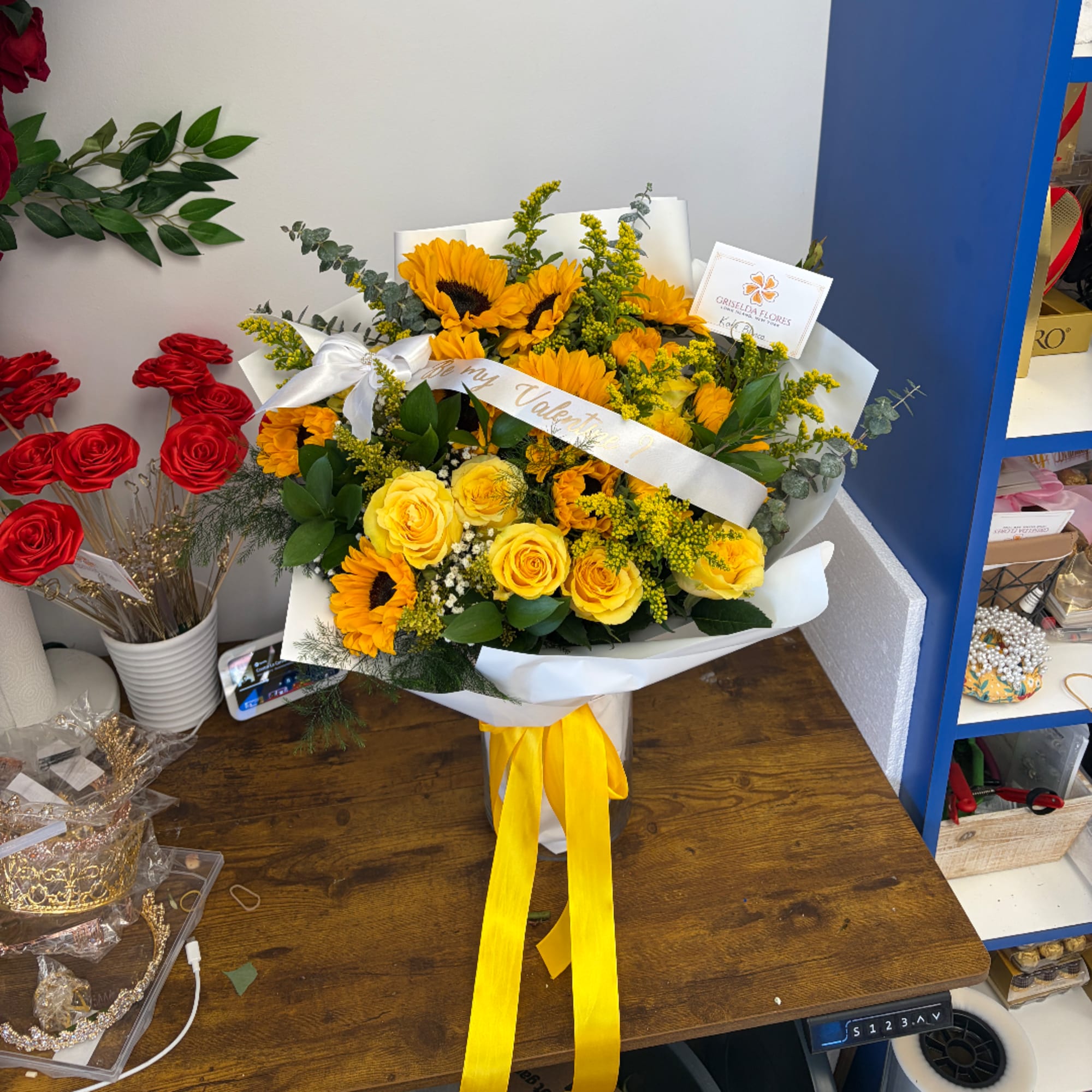 Yellow roses and sunflowers in white wrapping with a yellow ribbon