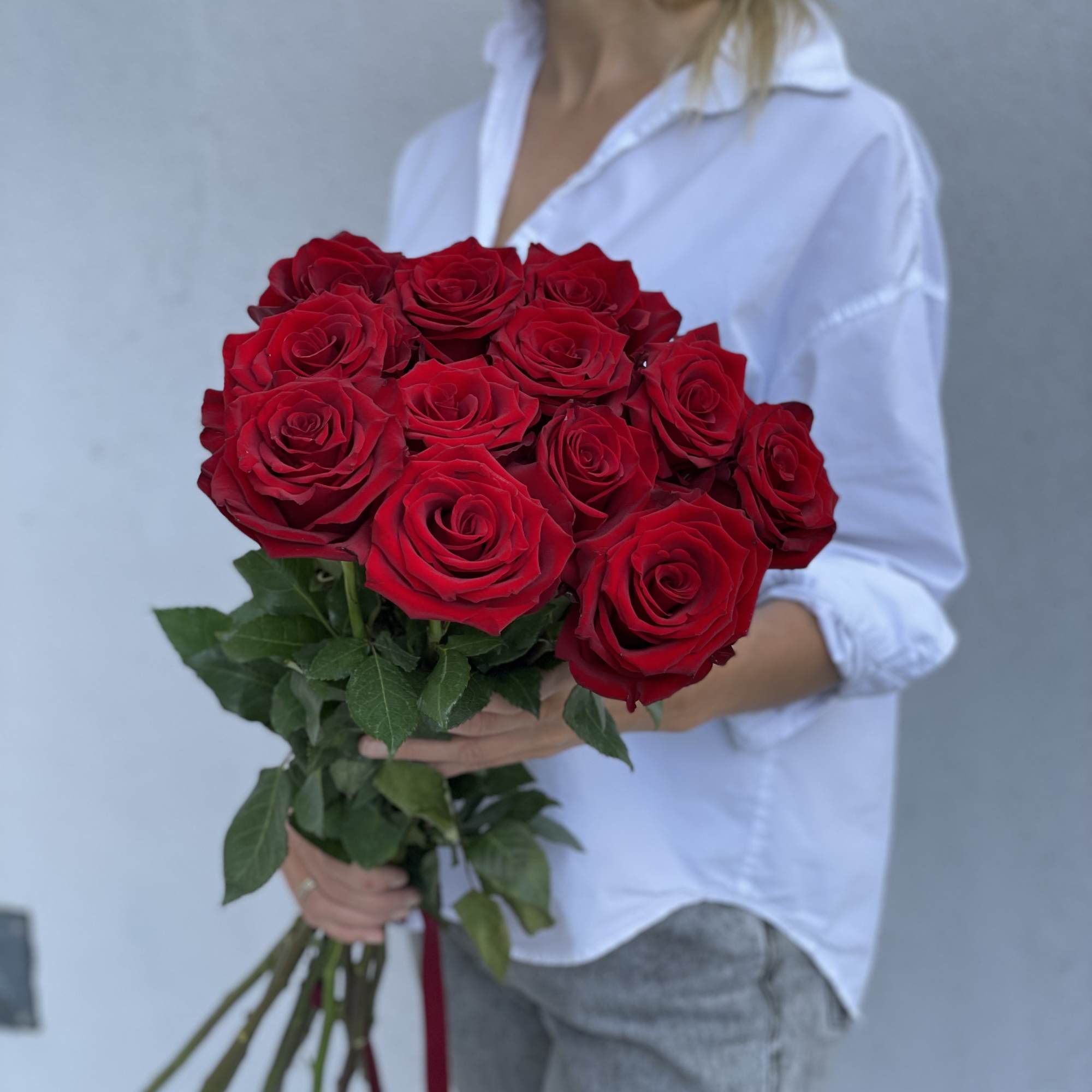 Bouquet of red roses held by a woman in a white shirt