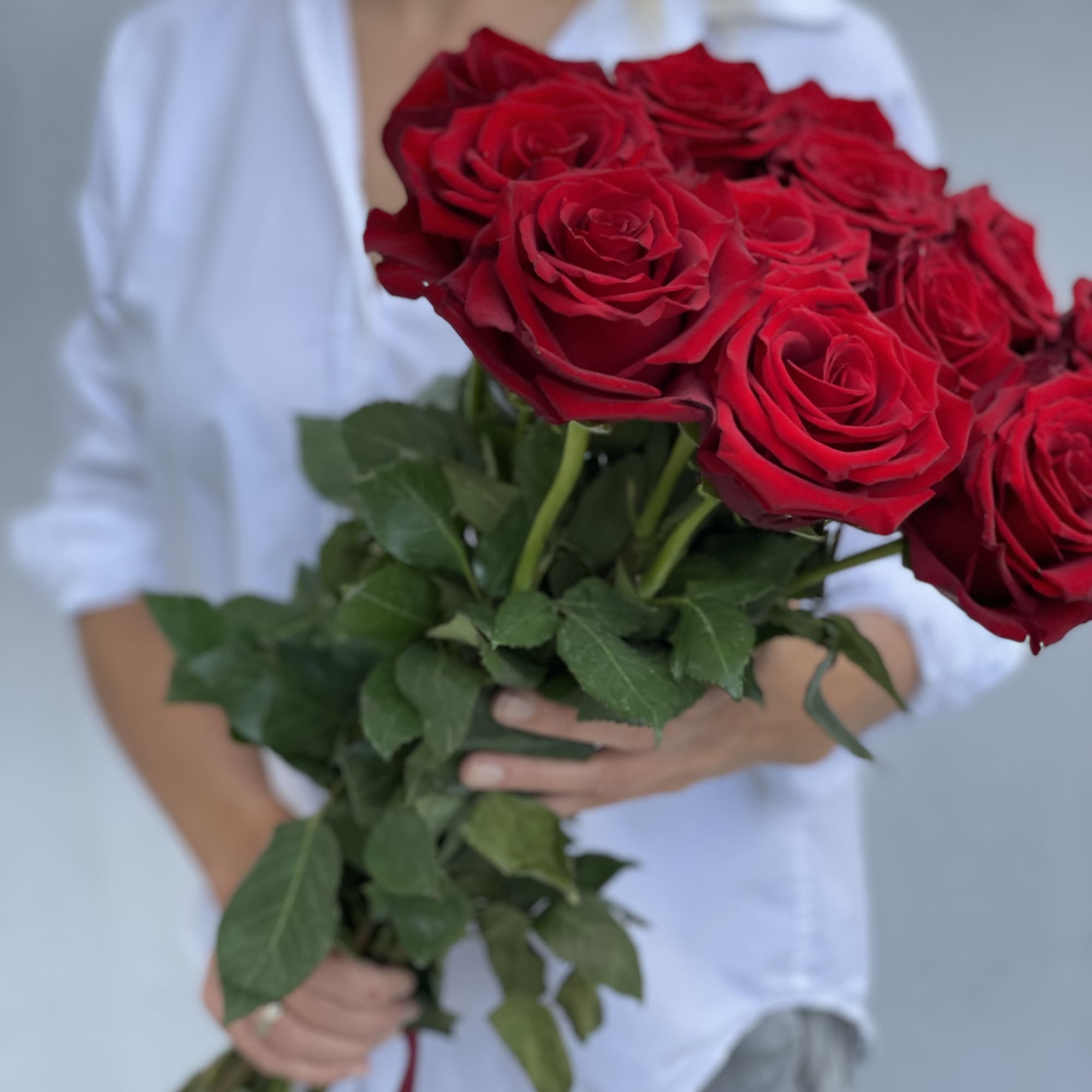 Person holding a bouquet of red roses