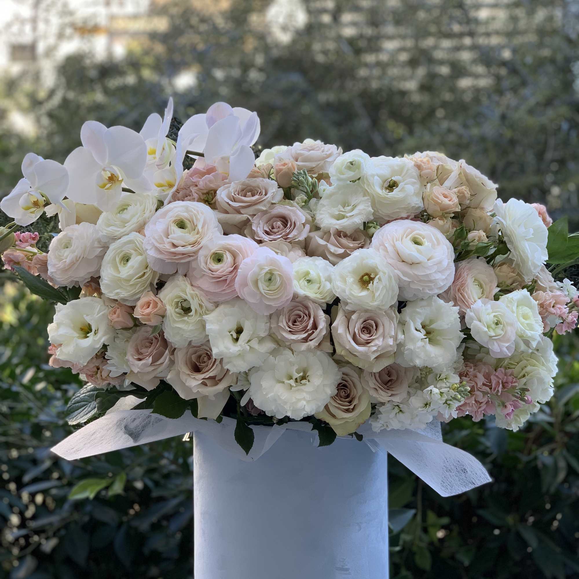 Blush and white bouquet in a tall white box with orchids and roses