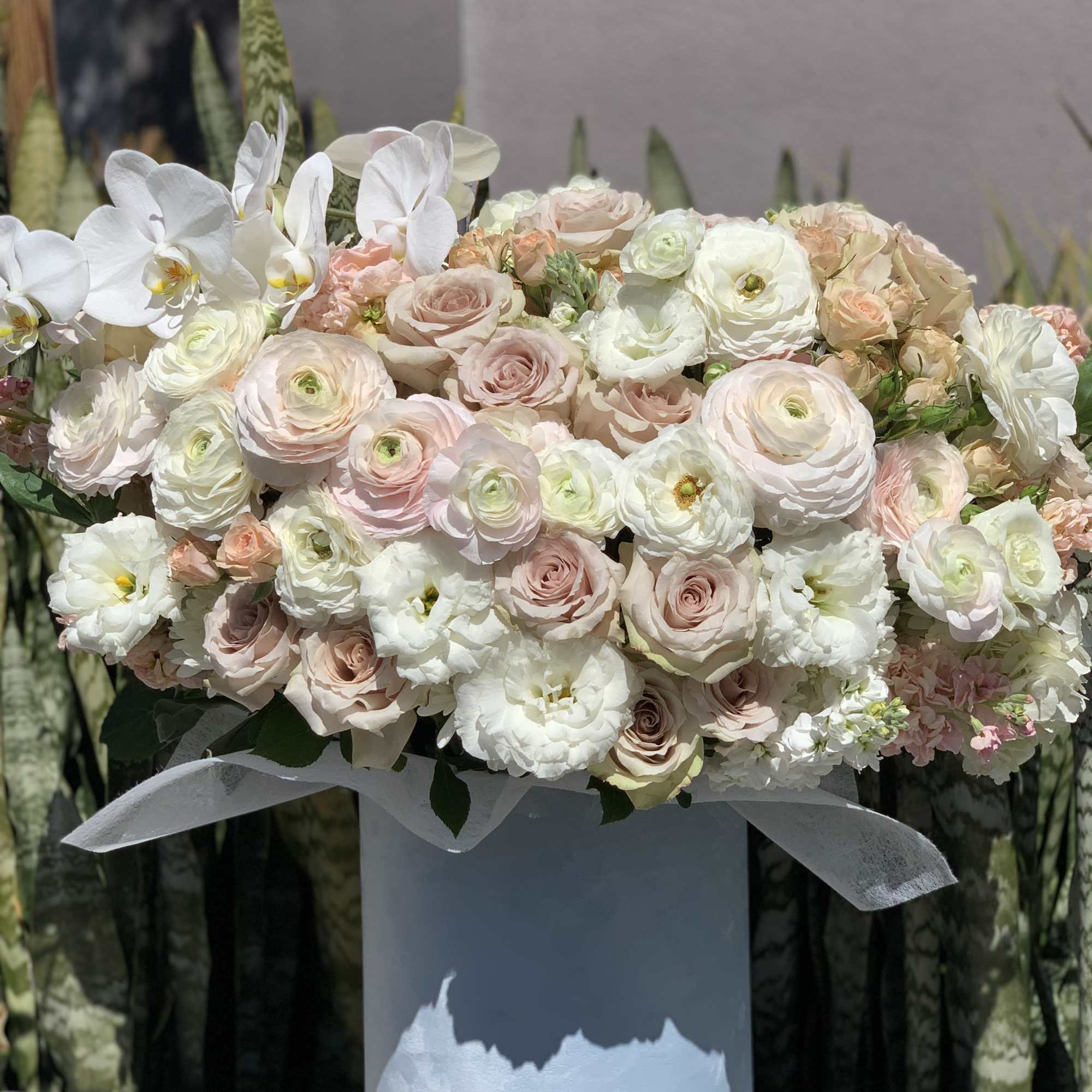 Large pastel bouquet of roses and white orchids in a blue vase