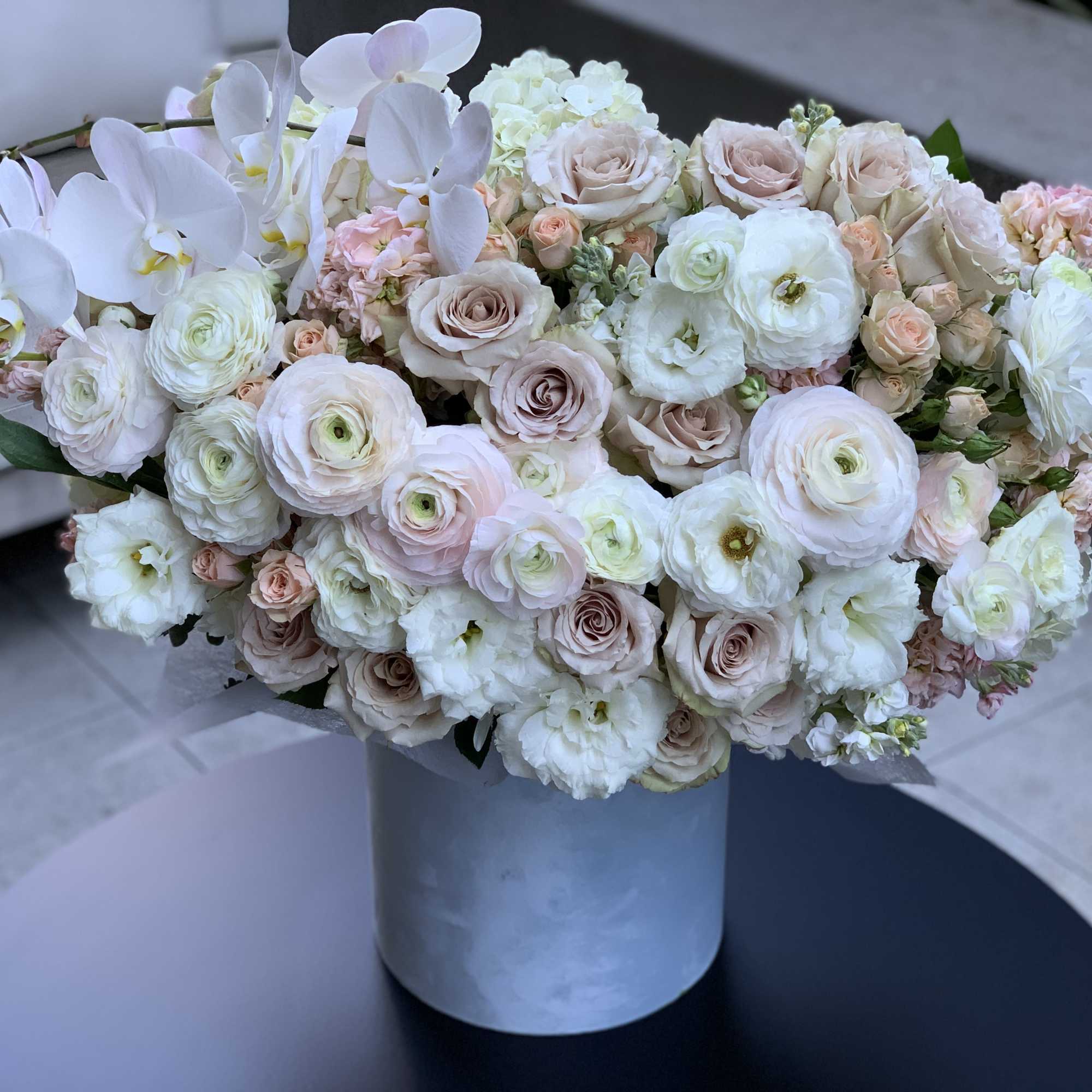 Blush and white bouquet in a gray cylindrical vase