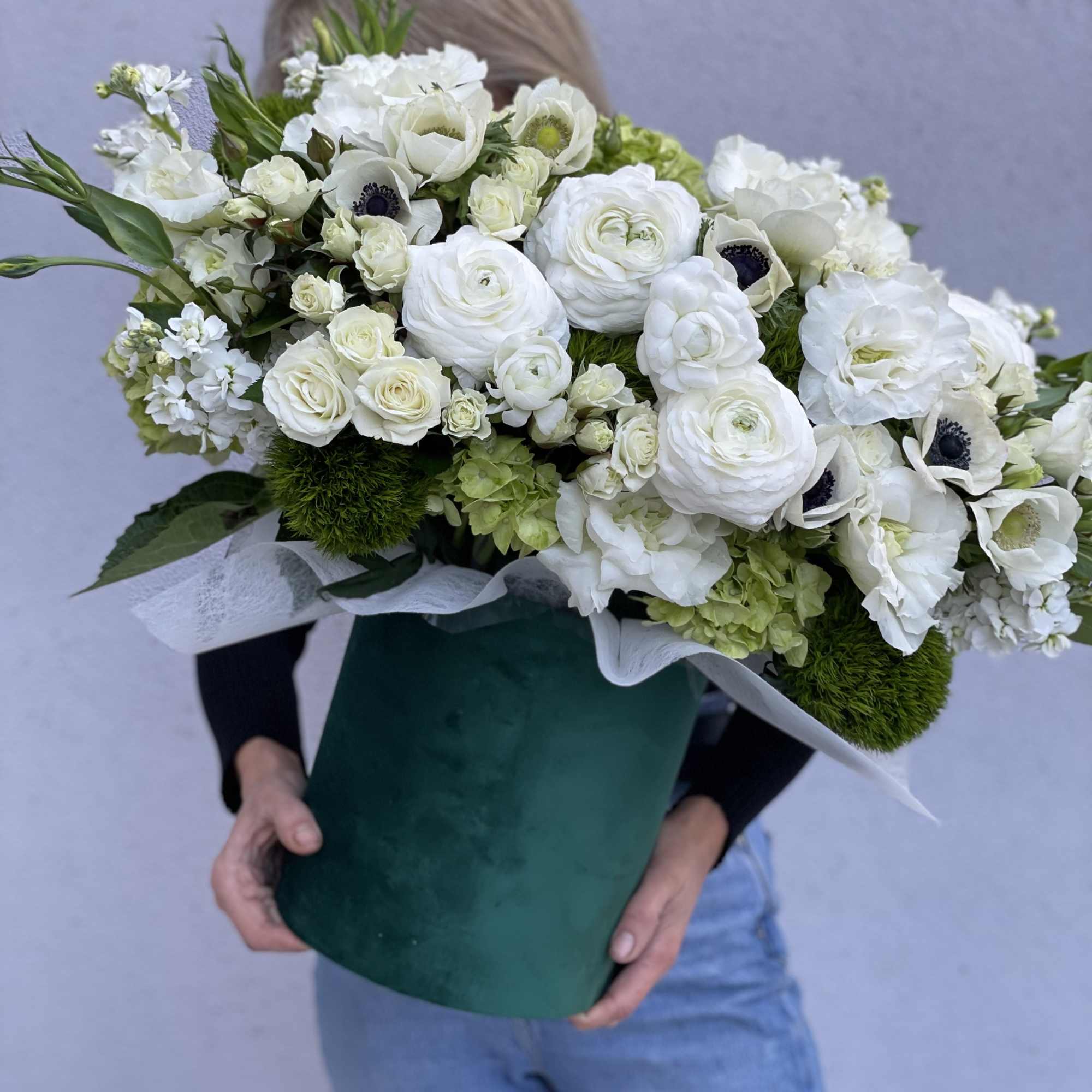 Large white bouquet with ranunculus, roses, and anemones in a green box