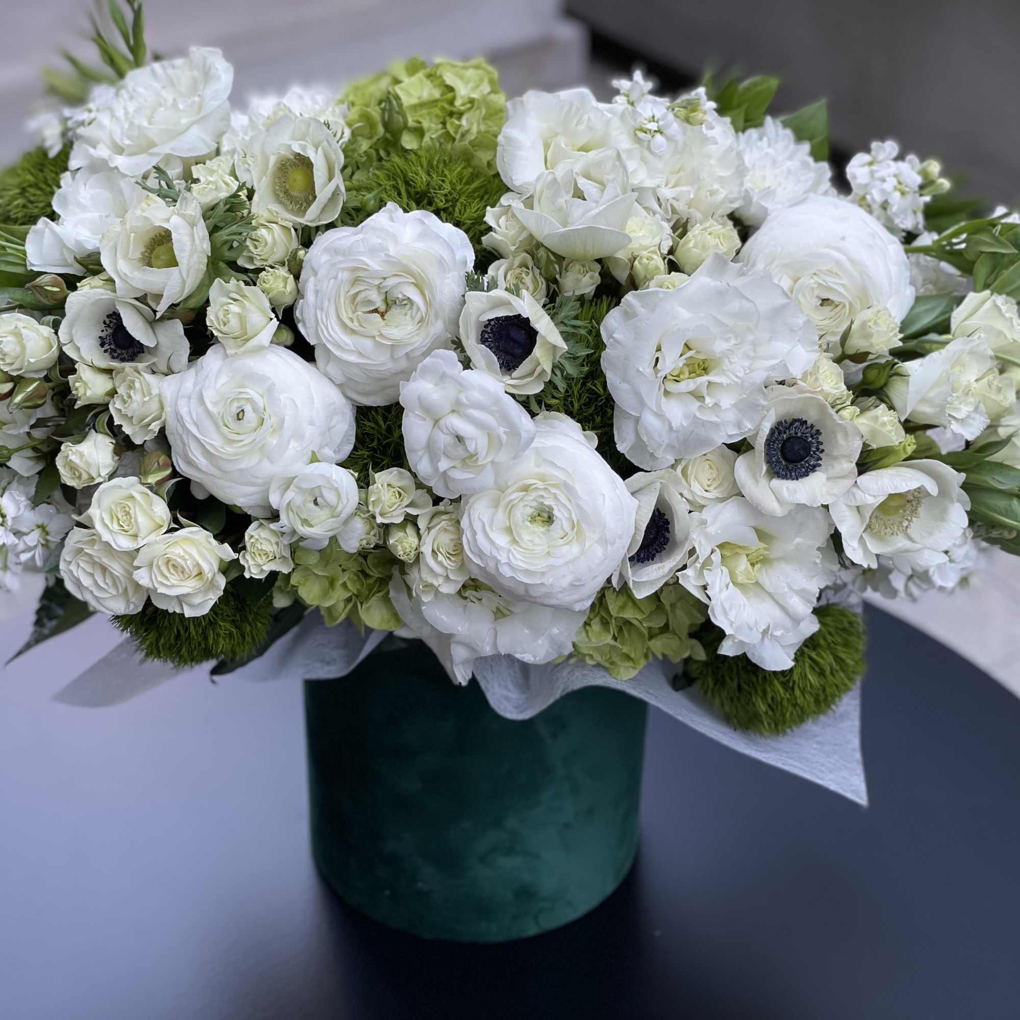 White floral arrangement in a green velvet vase