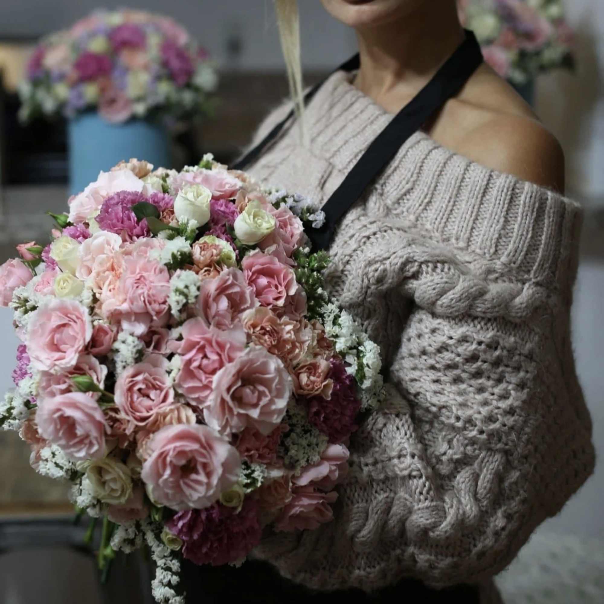 Woman holding a large bouquet of pink roses and carnations