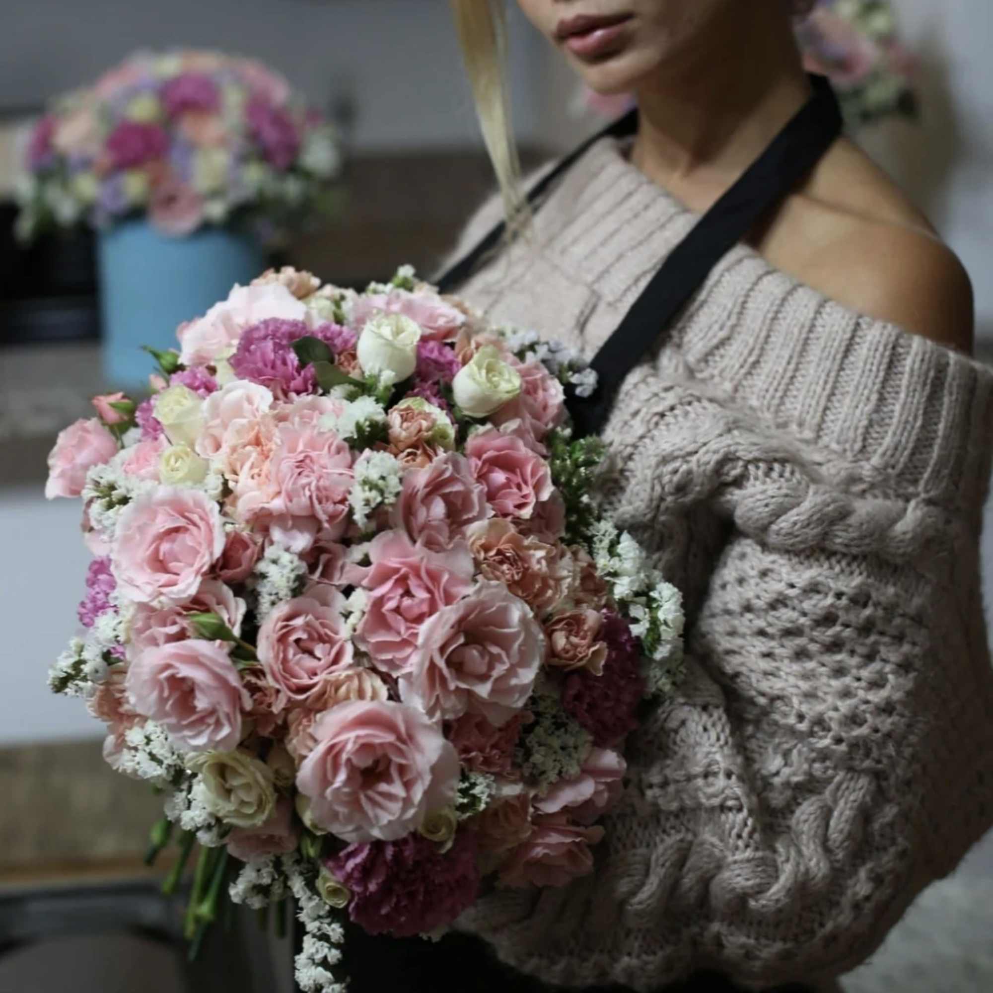 Woman holding a large bouquet of pink roses and small white filler flowers