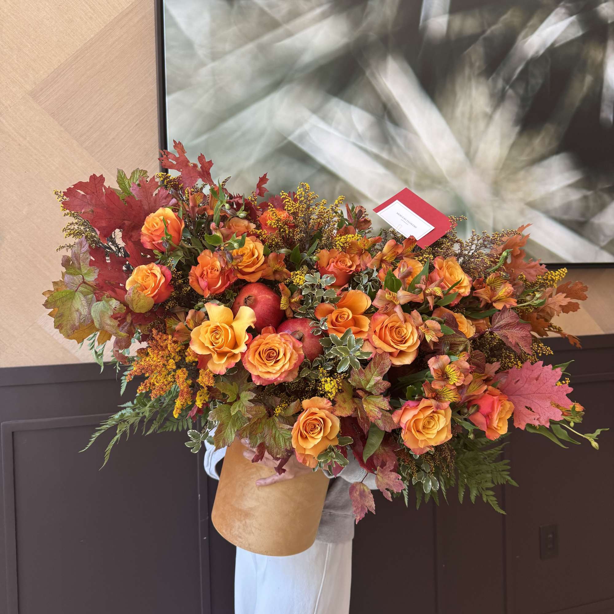 Large bouquet of orange roses with autumn leaves and red apples