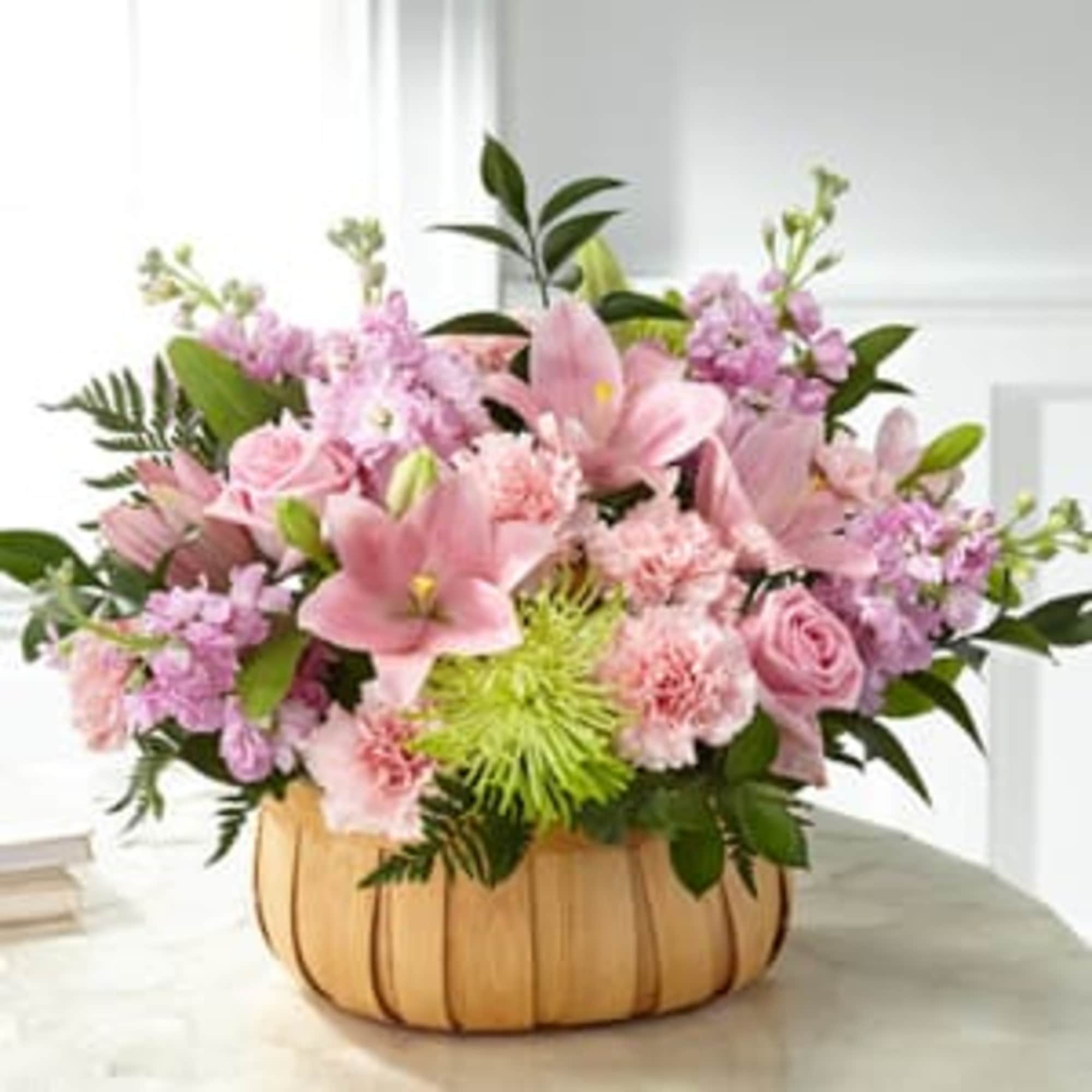Pink mixed flower arrangement in a wooden basket container