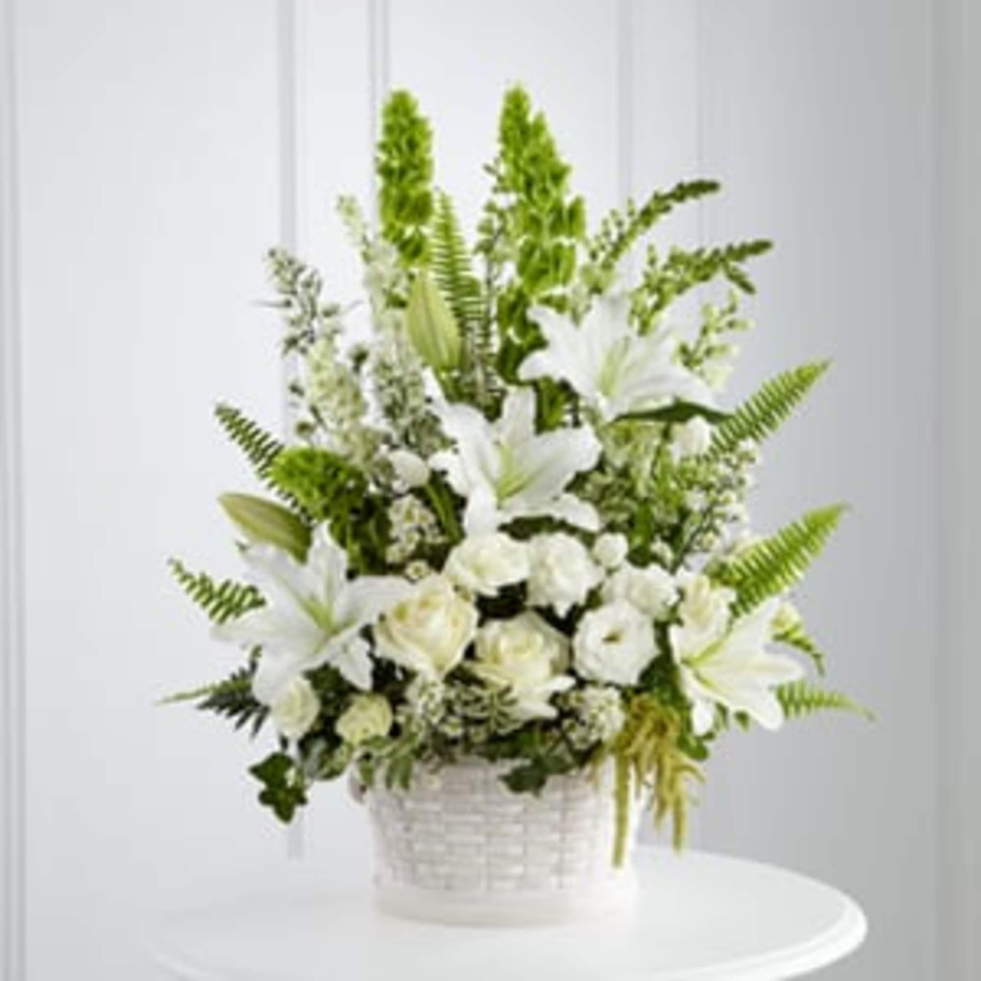 White lilies and roses in a white basket arrangement