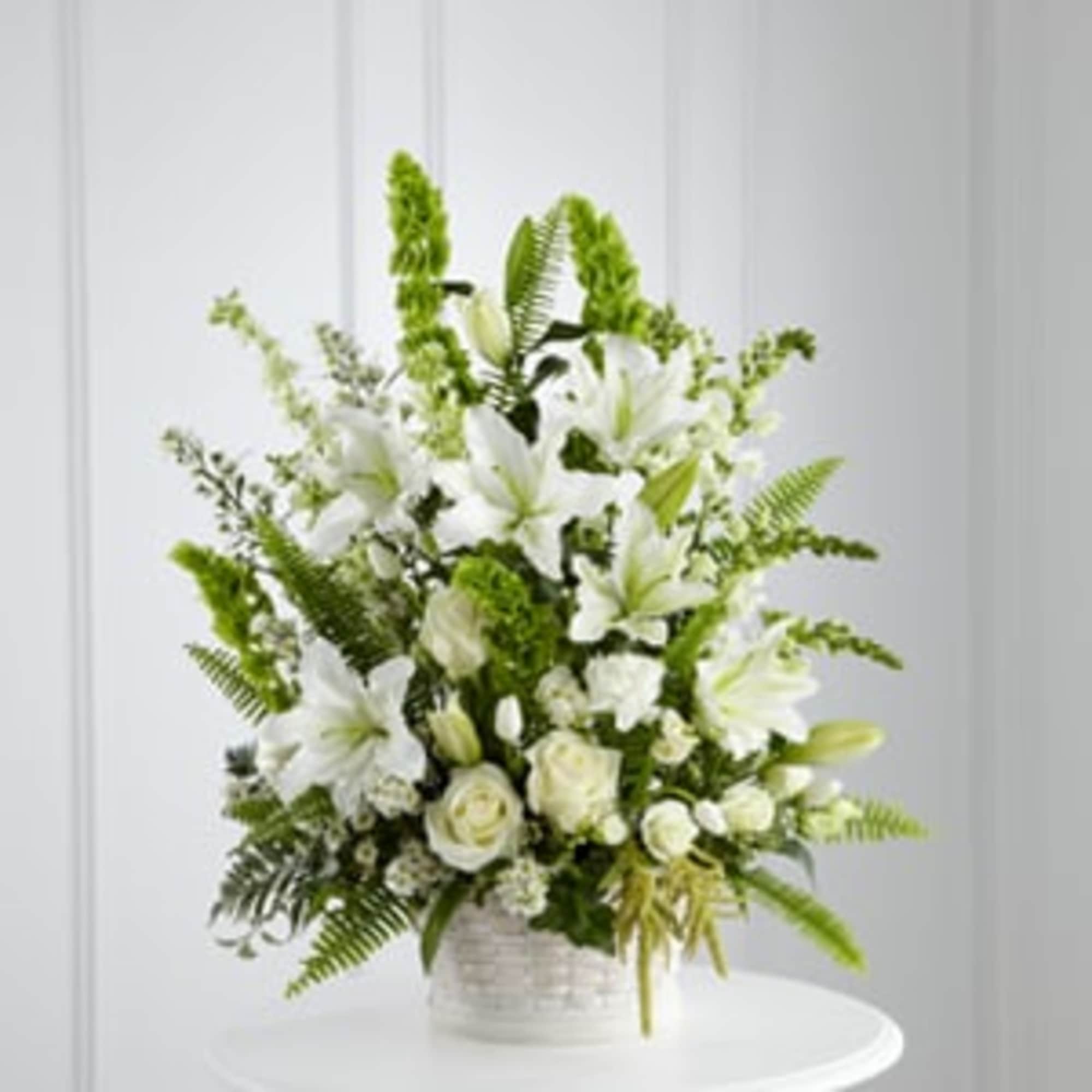 White lilies and roses in a white basket with green foliage