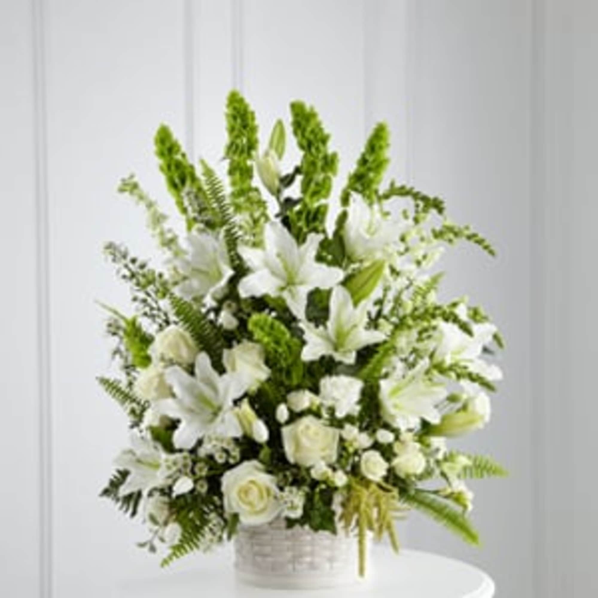 White lilies and roses arranged in a white basket