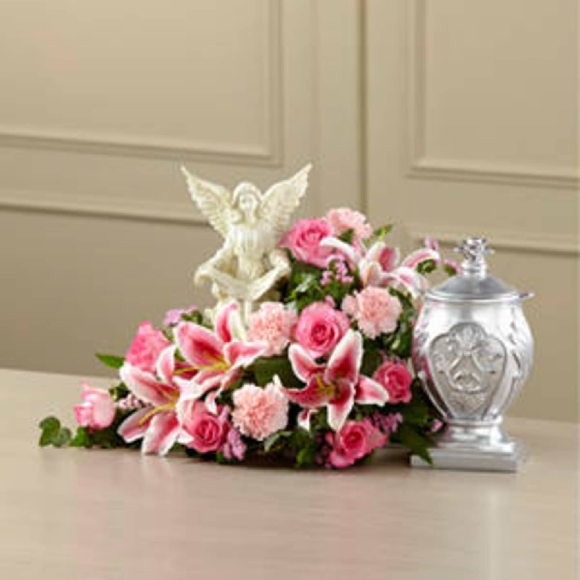 Pink floral casket spray with an angel figurine and silver urn