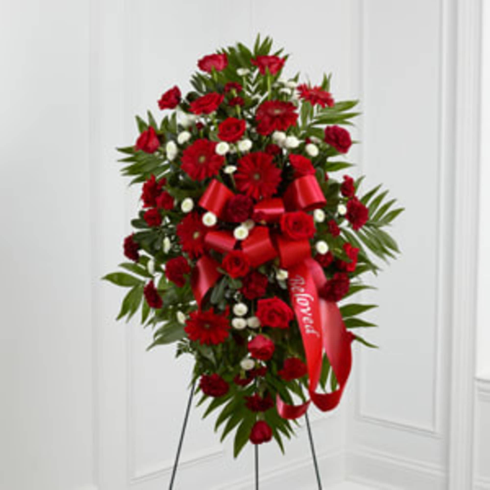 Tall red floral standing spray with a red ribbon on an easel