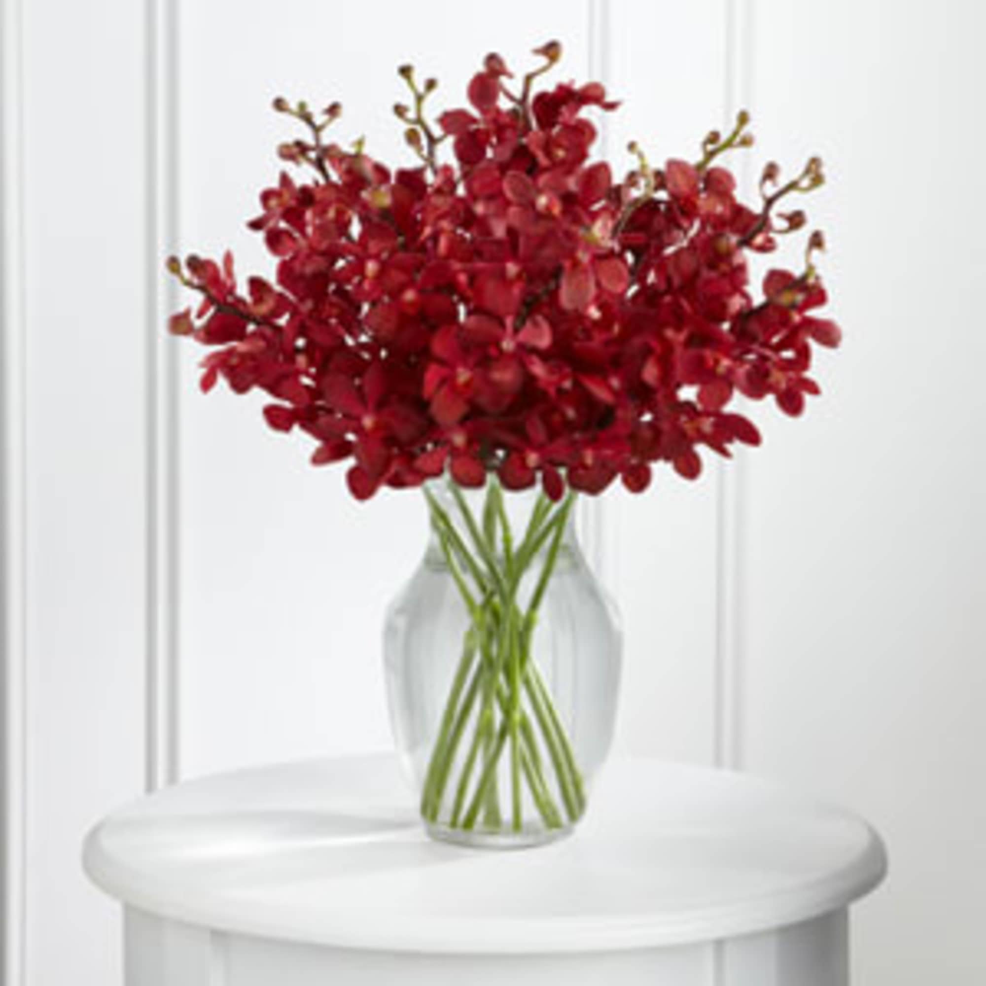 Red orchid arrangement in a clear glass vase