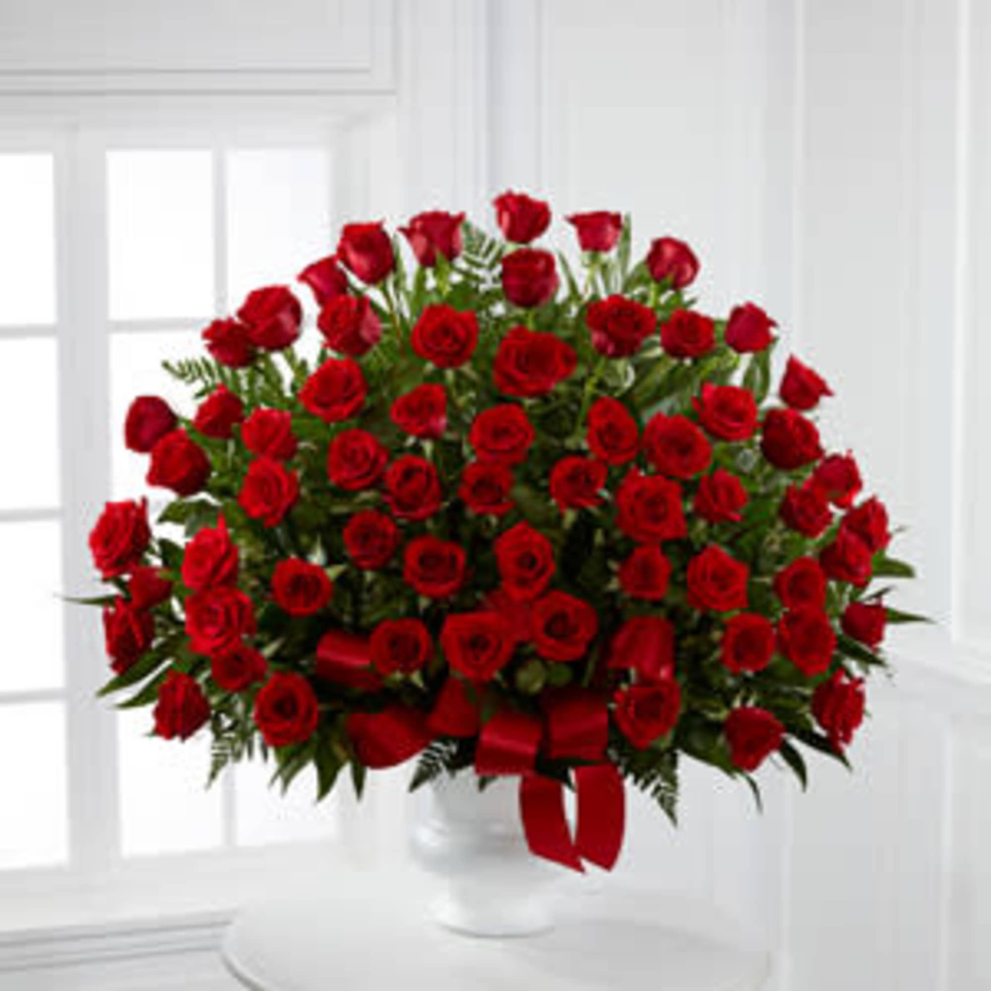 Large bouquet of red roses in a white vase with a red ribbon
