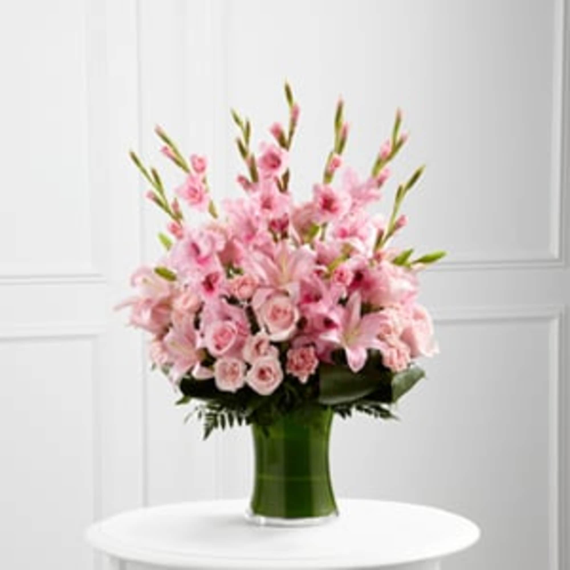 Pink lilies and roses arranged in a green vase