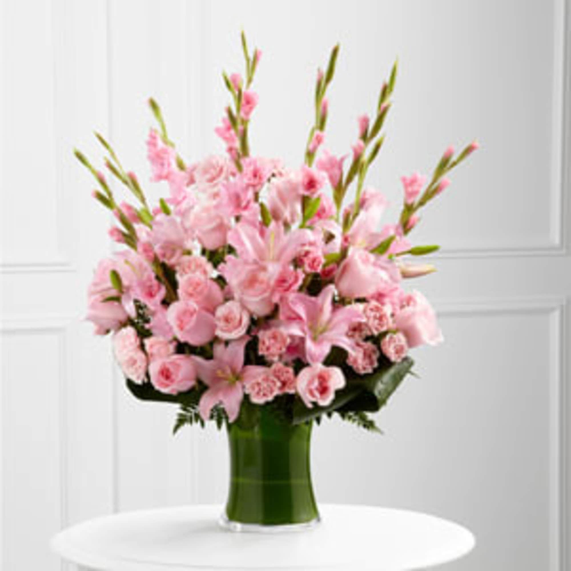 Pink lilies and roses arranged in a green glass vase