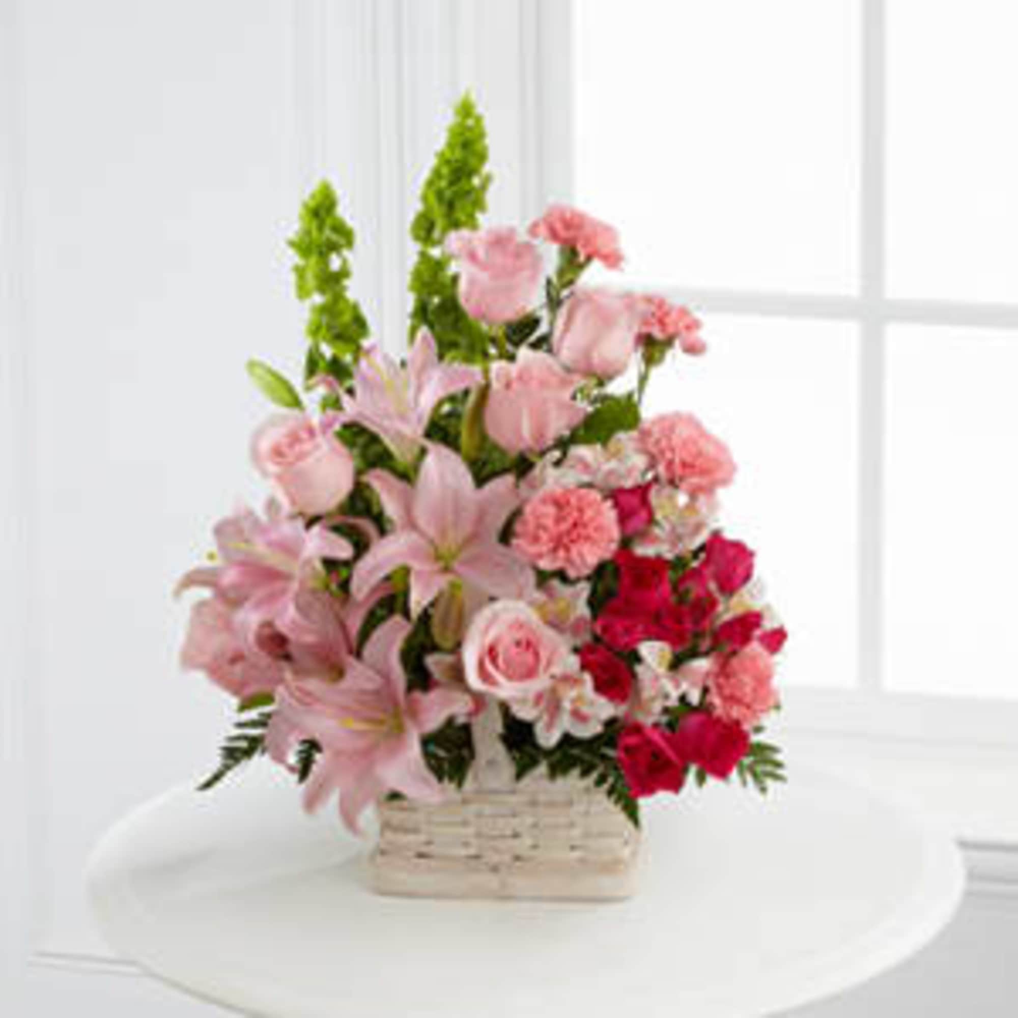 Pink lilies and roses arranged in a wicker basket