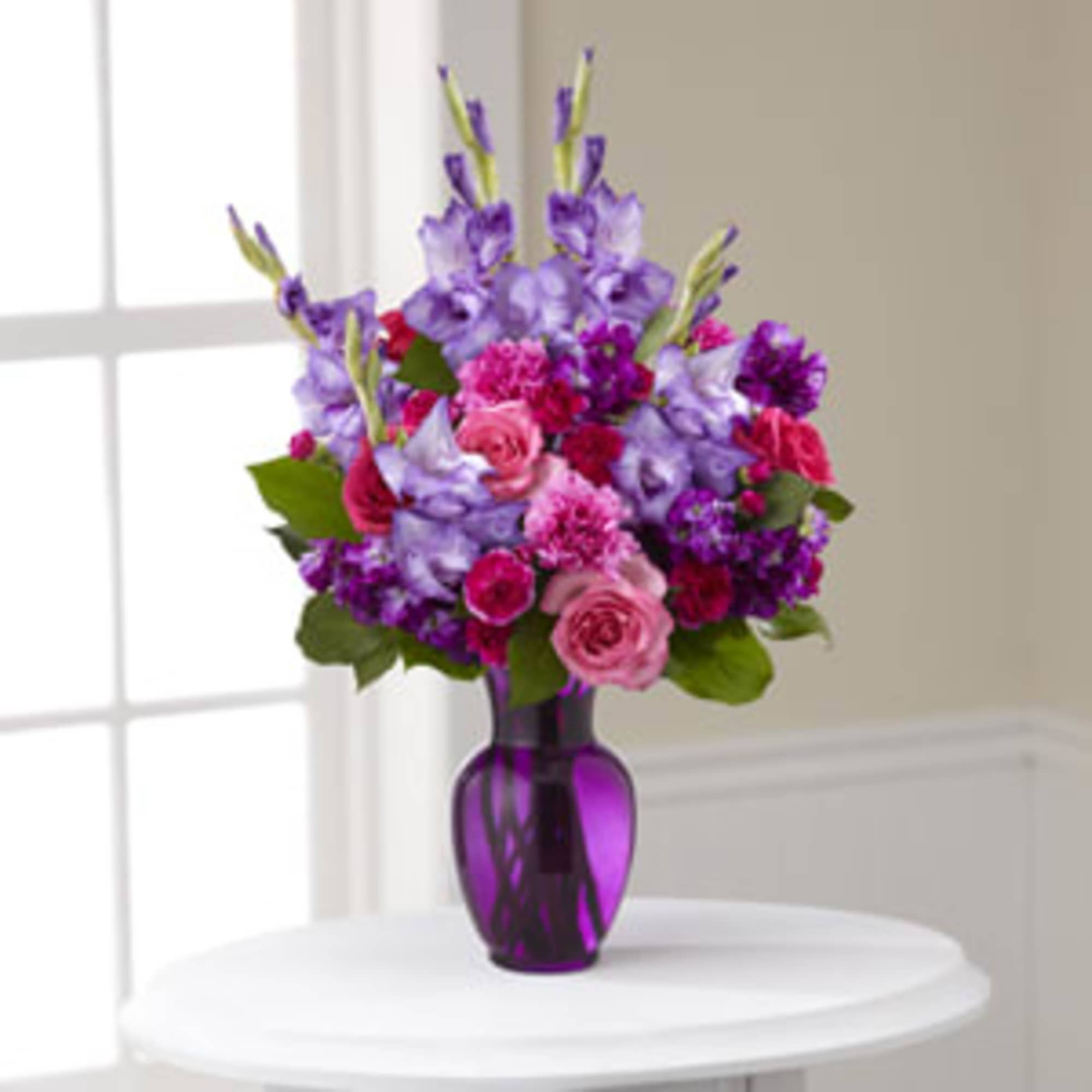 Purple and pink mixed bouquet in a purple glass vase