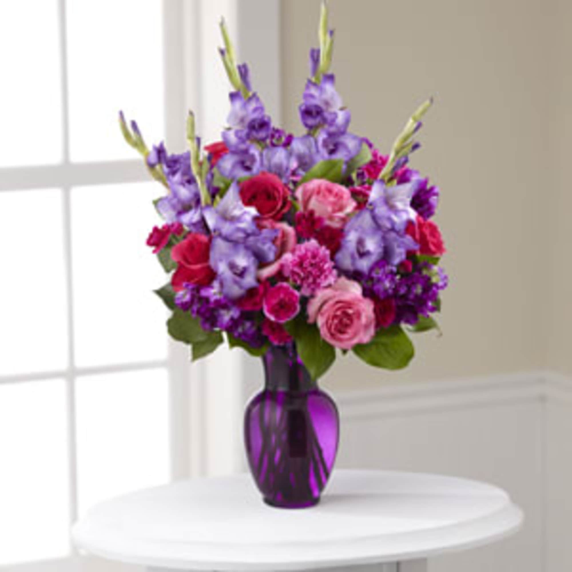 Purple and pink flower bouquet in a purple glass vase