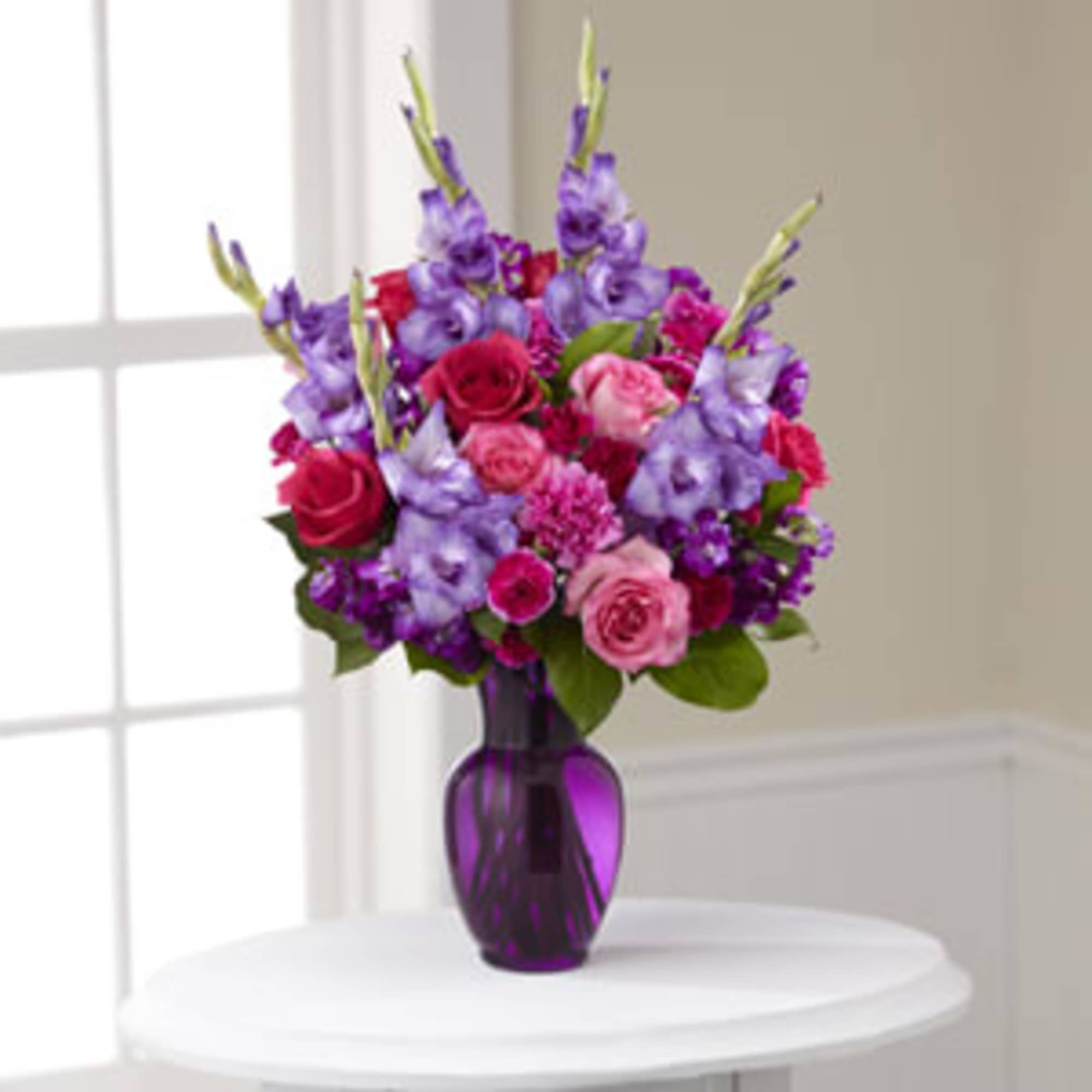 Purple and pink flower arrangement in a purple glass vase