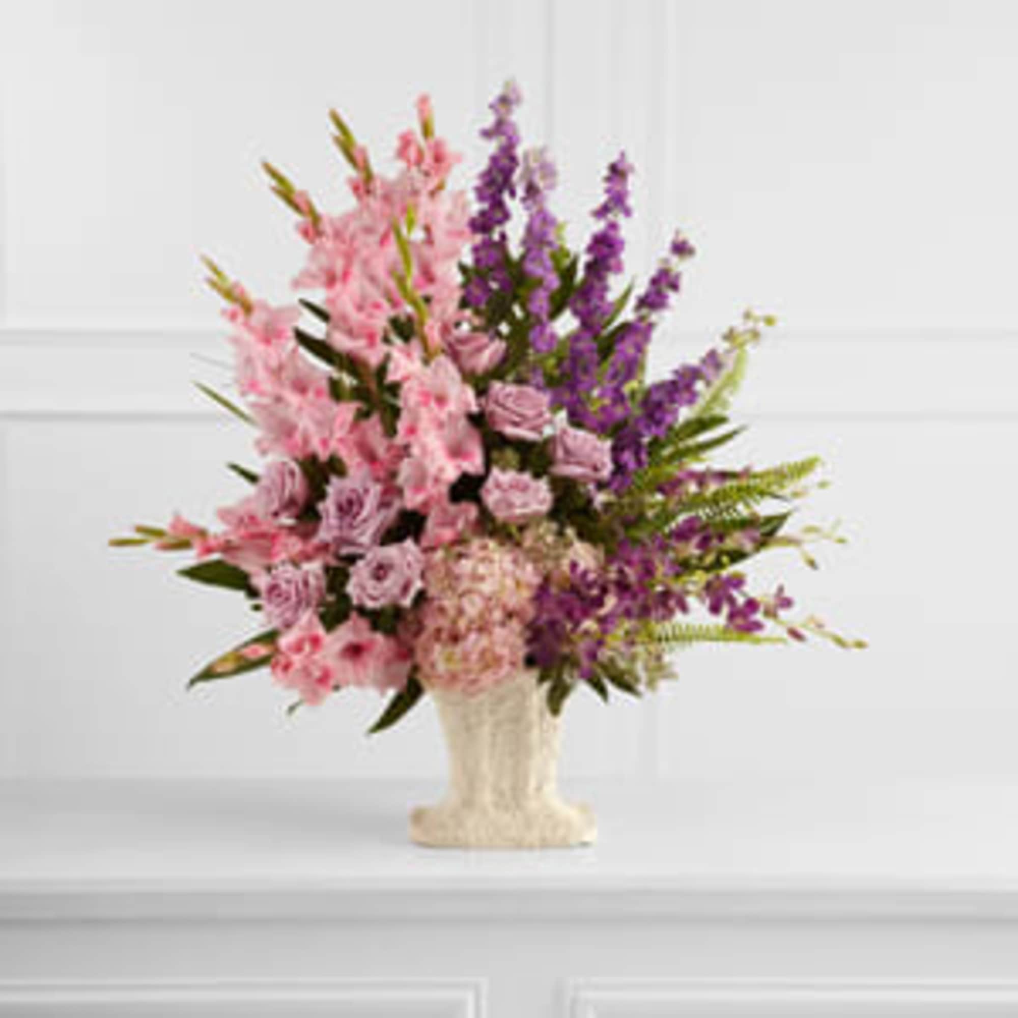 Pink and purple floral arrangement in a cream vase