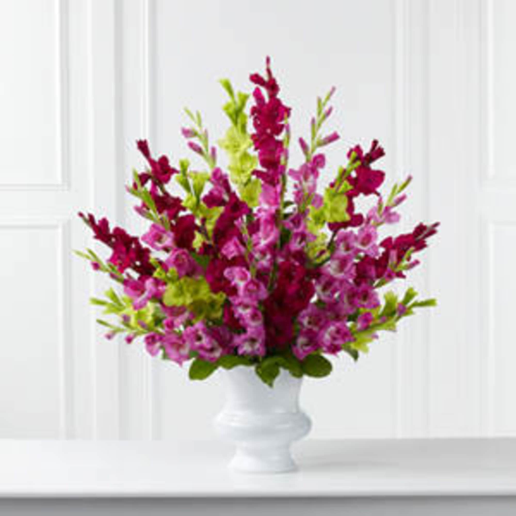Pink and magenta flowers arranged in a white vase