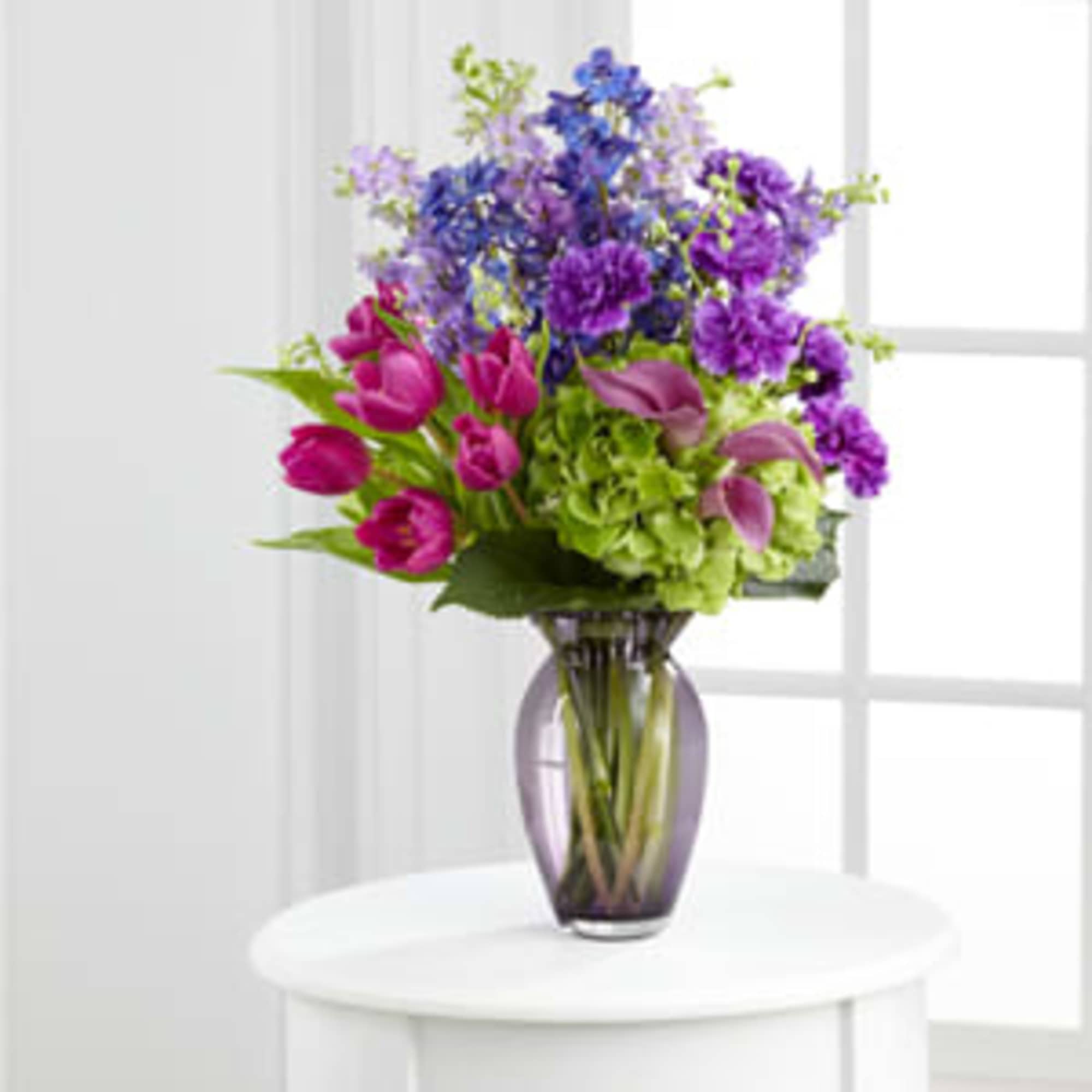 Bouquet of purple, pink, and green flowers in a glass vase