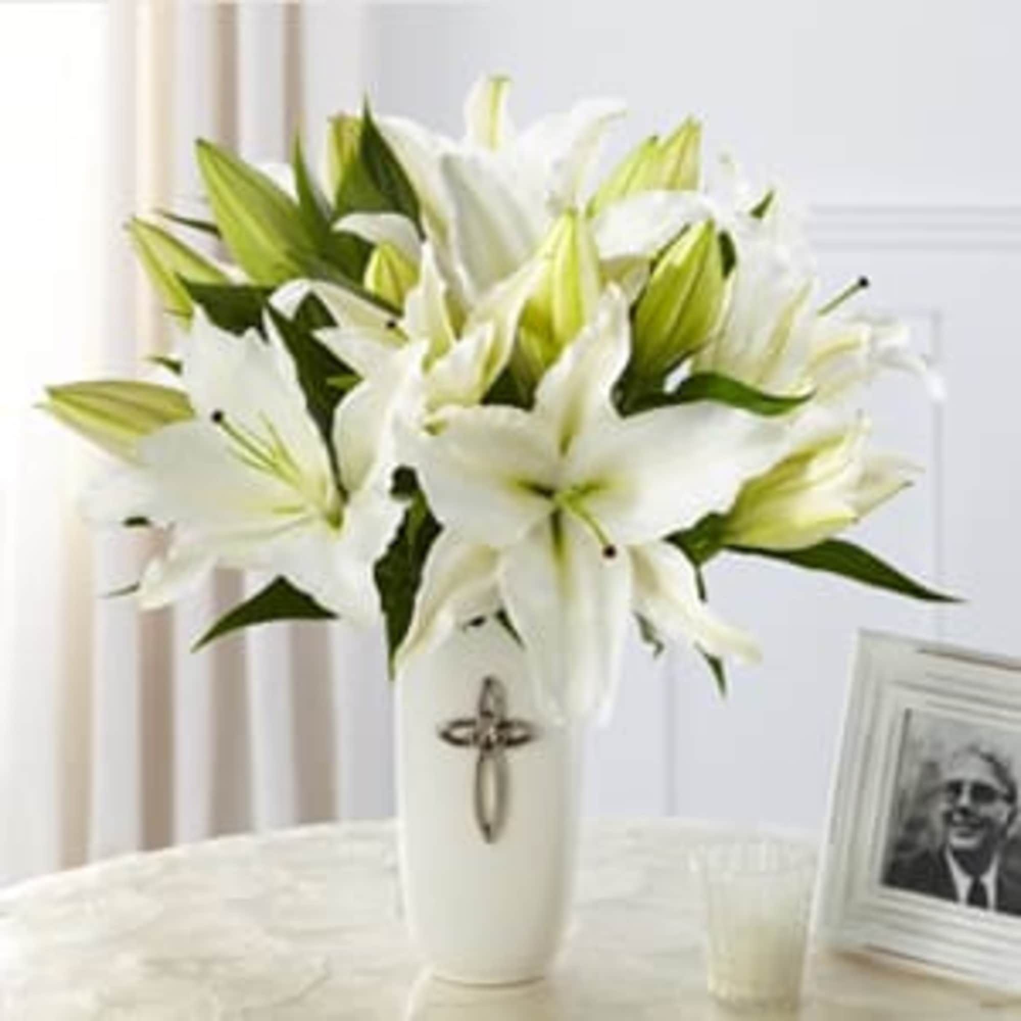 White lilies arranged in a tall white vase