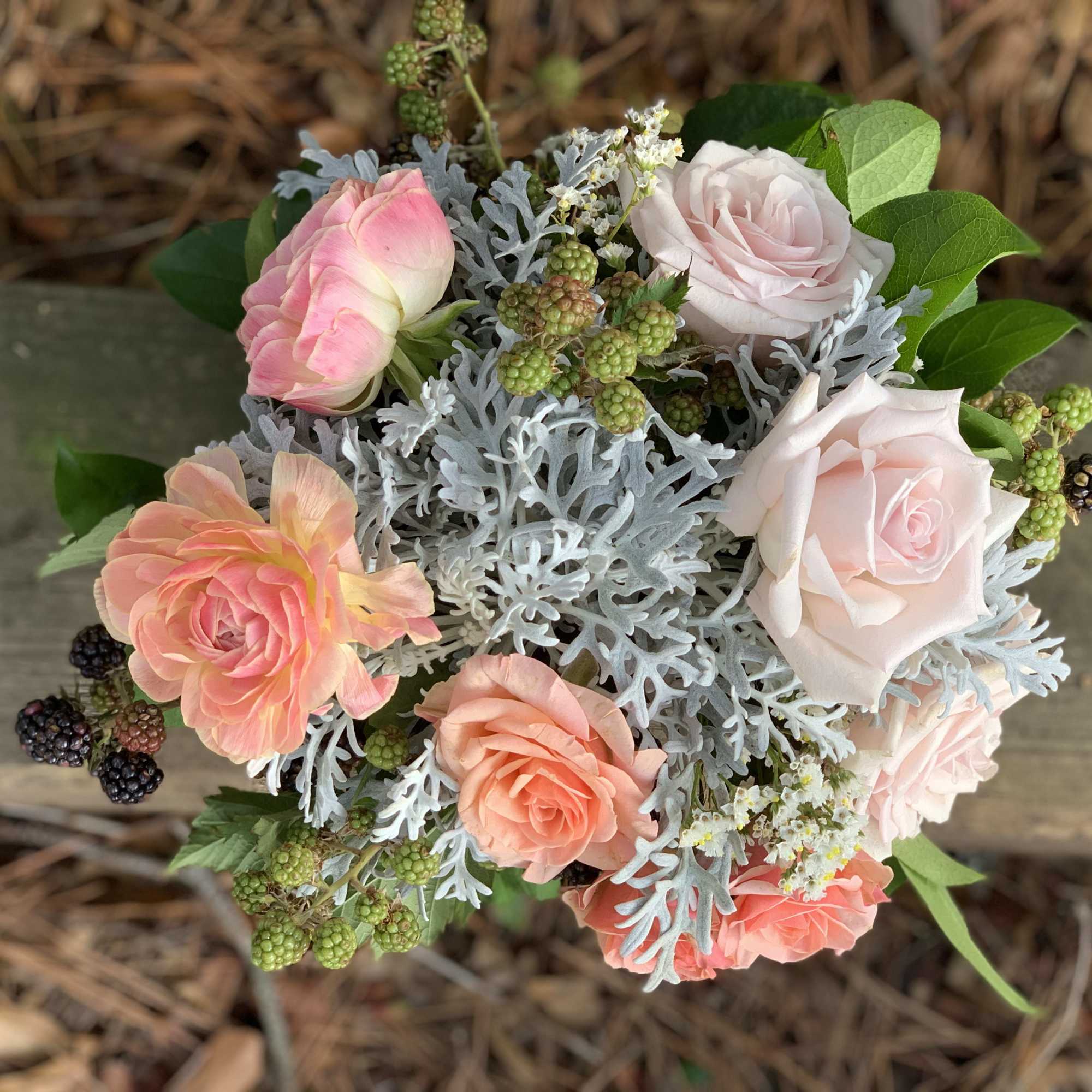 Bouquet of pink and blush roses with silvery foliage and berries