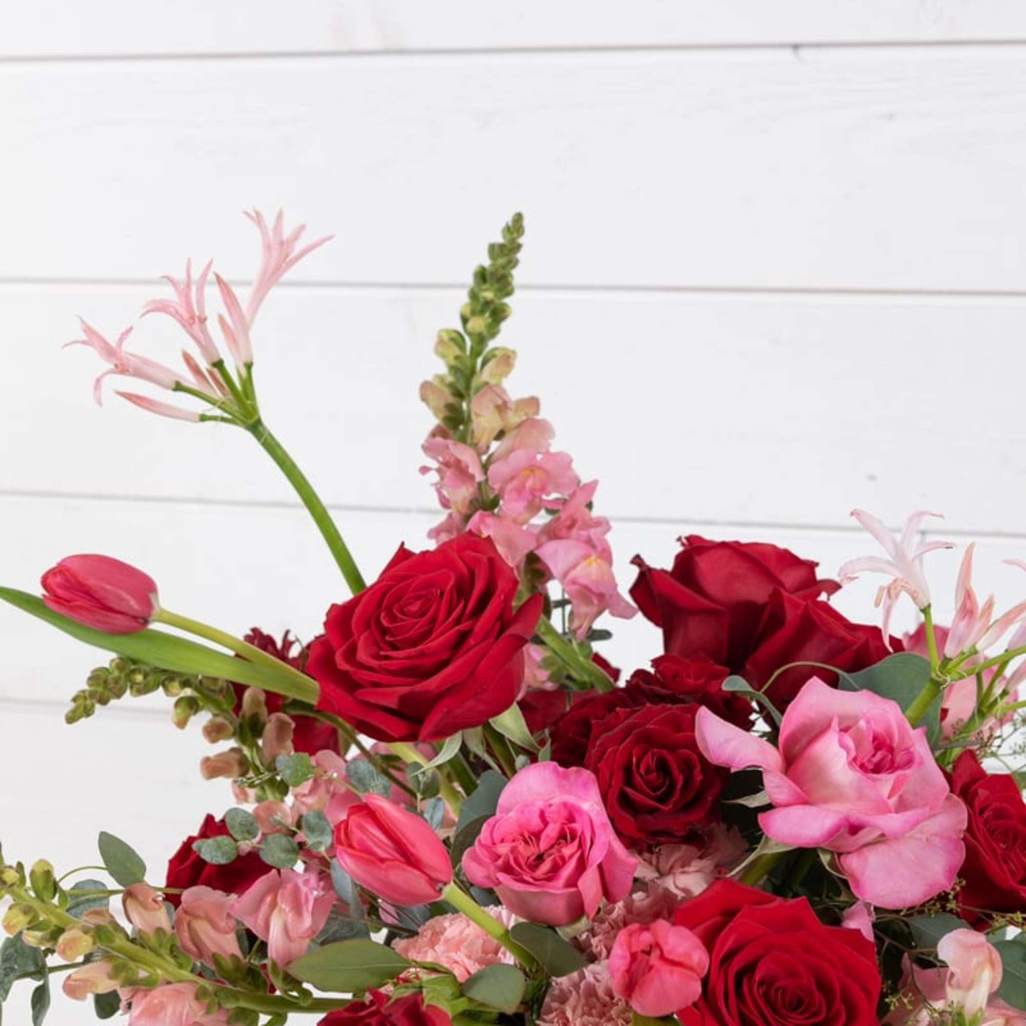 Bouquet of red and pink roses with tulips in a glass vase