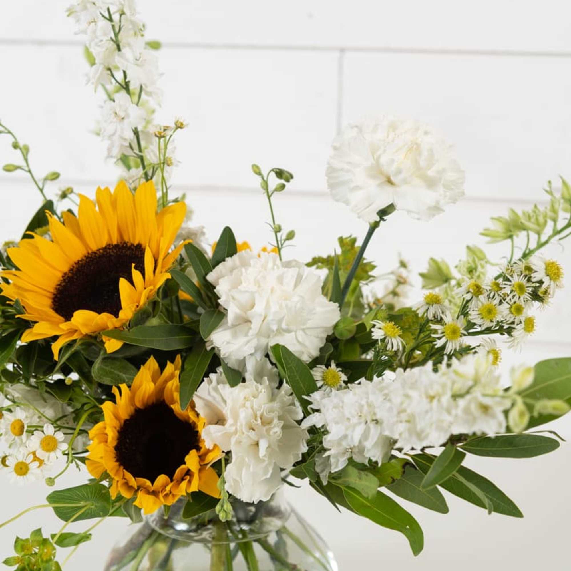 Sunflowers and white flowers arranged in a clear glass vase