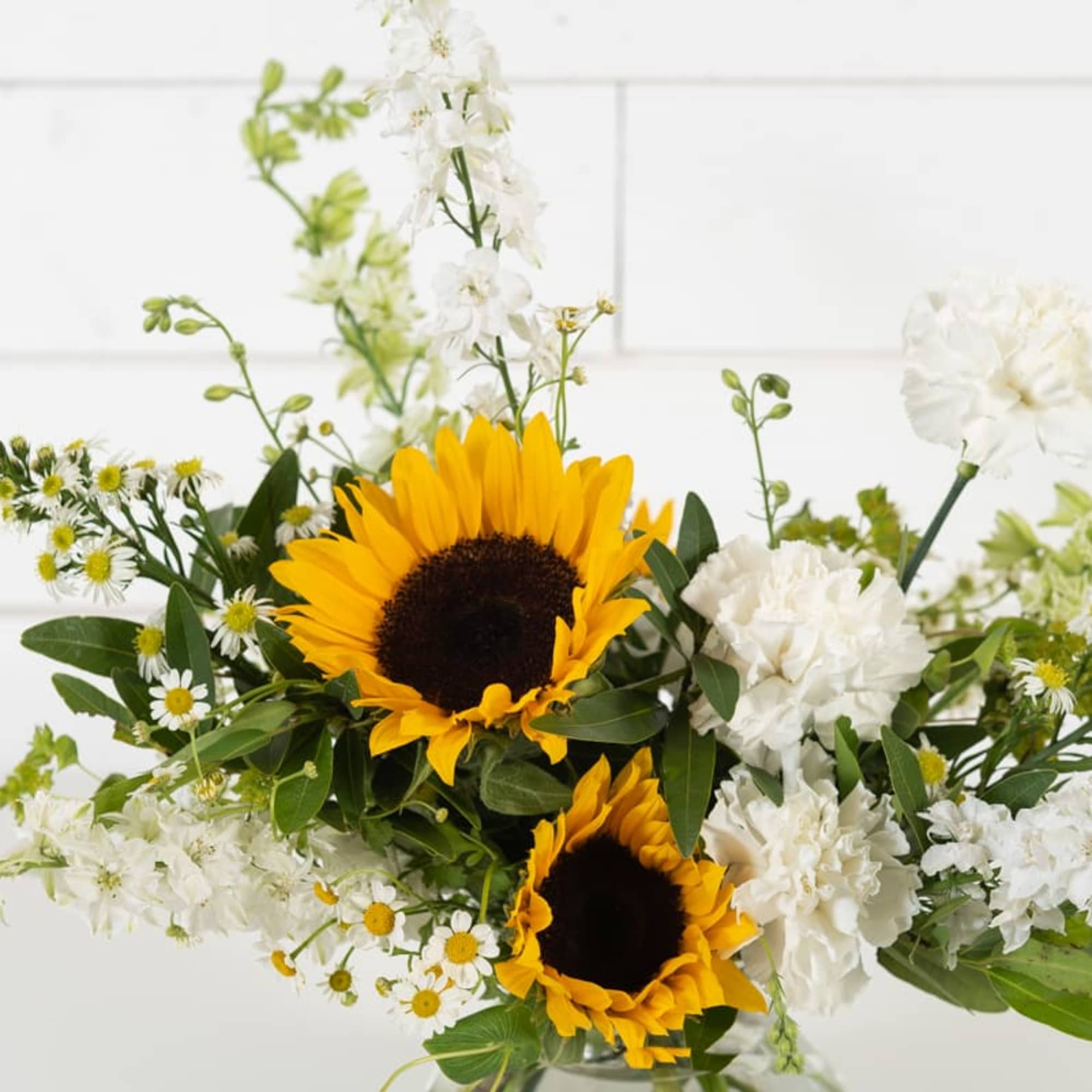 Sunflowers and white flowers in a clear vase