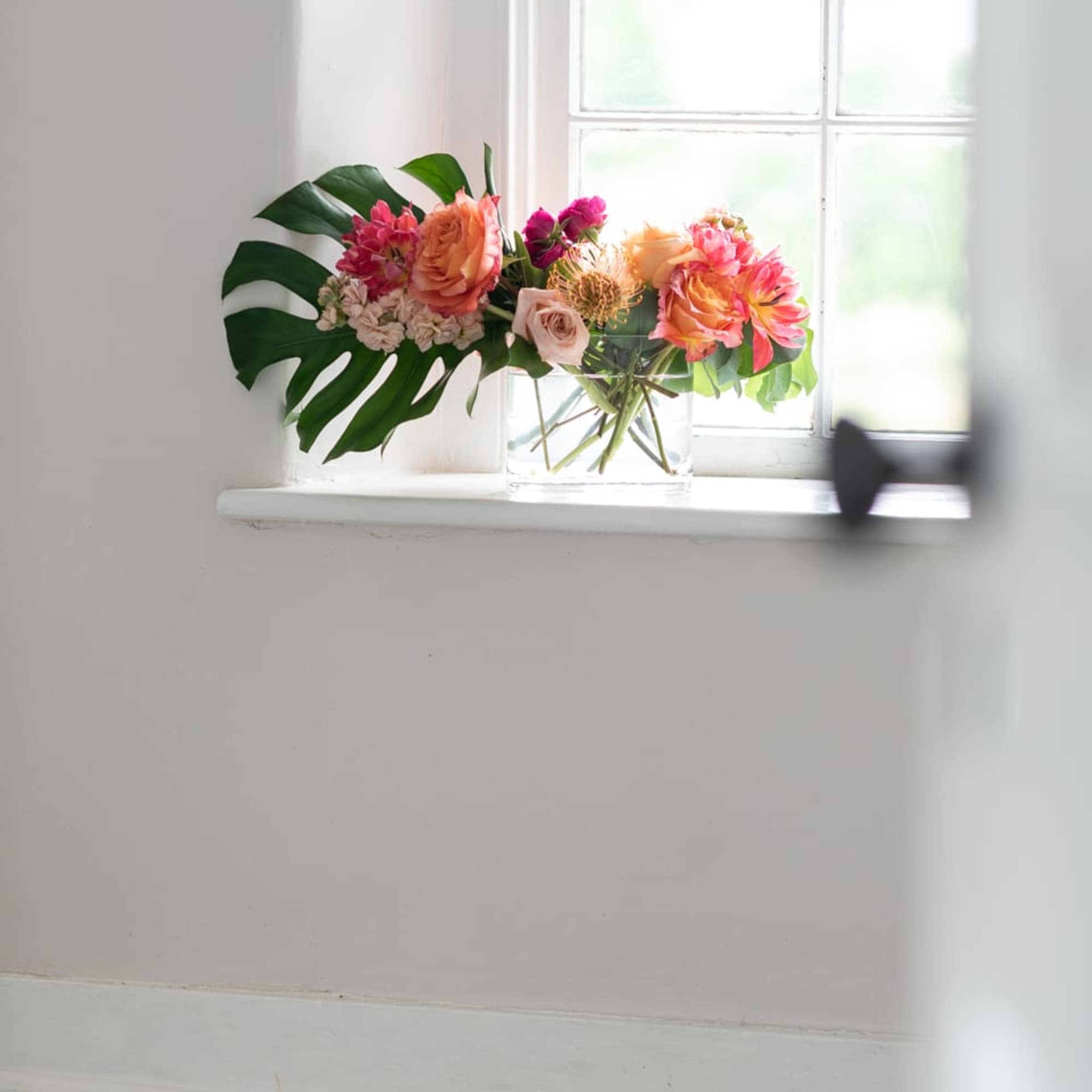 Mixed bouquet of pink and peach flowers in a clear glass vase