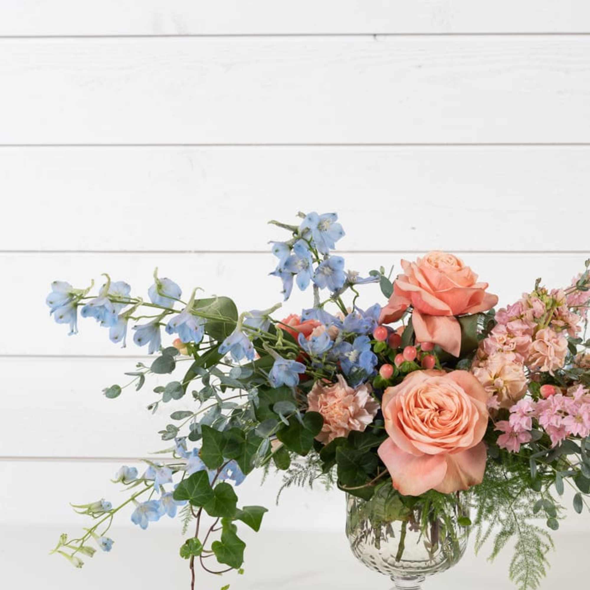 Peach roses and blue flowers in a clear glass vase, photo 5 of 5
