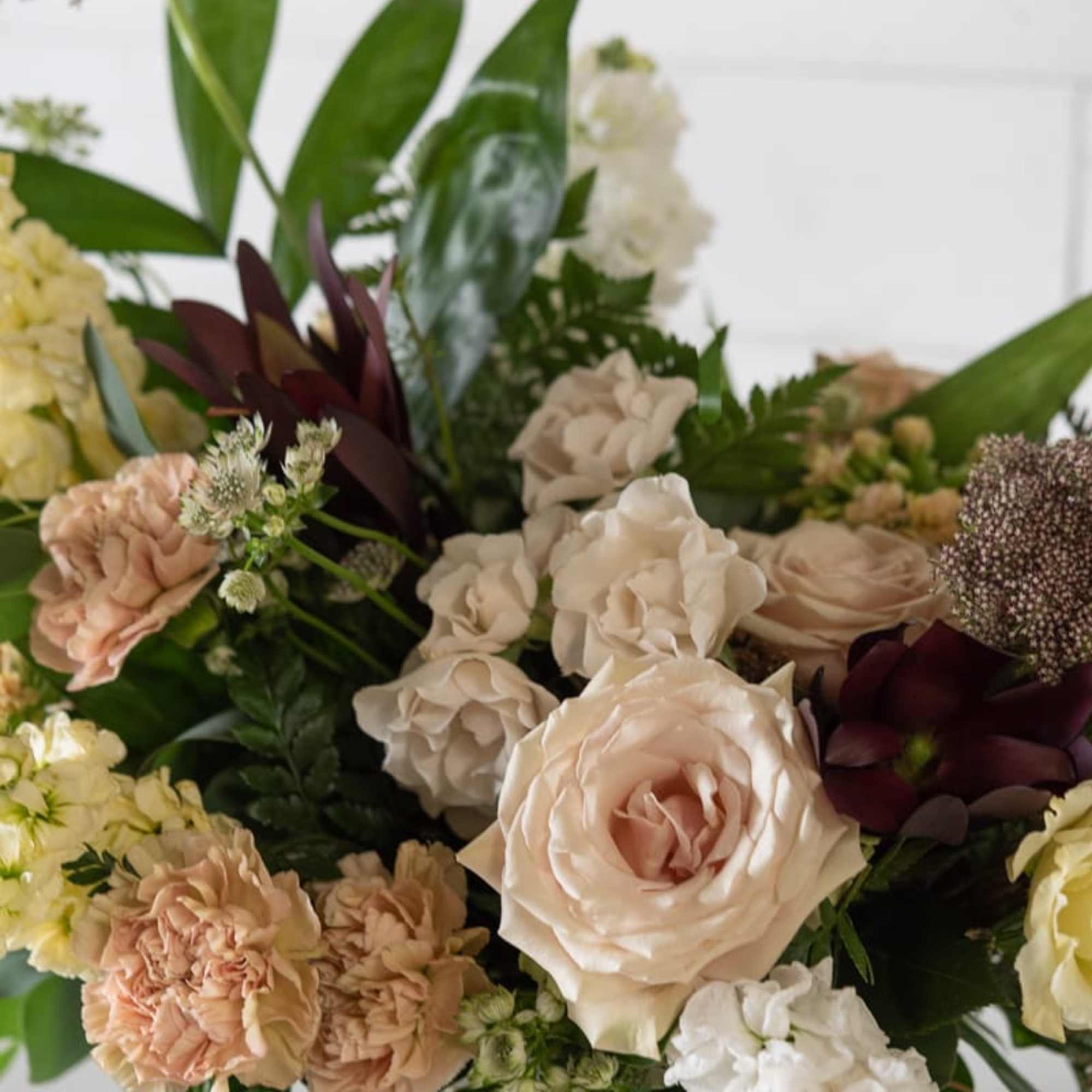Mixed bouquet of blush roses and cream carnations in a glass vase