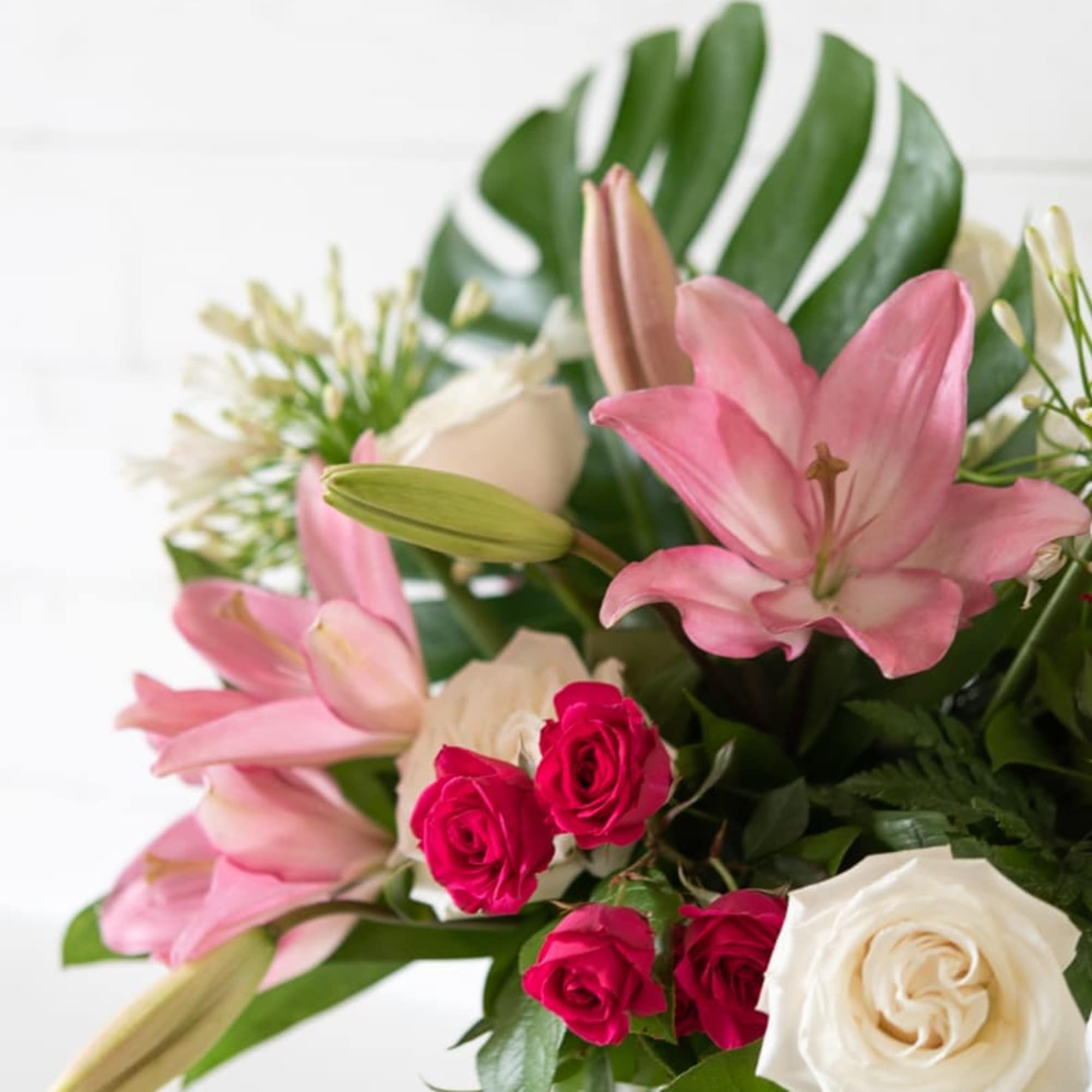 Pink lilies and roses arranged in a glass vase, photo 3 of 4
